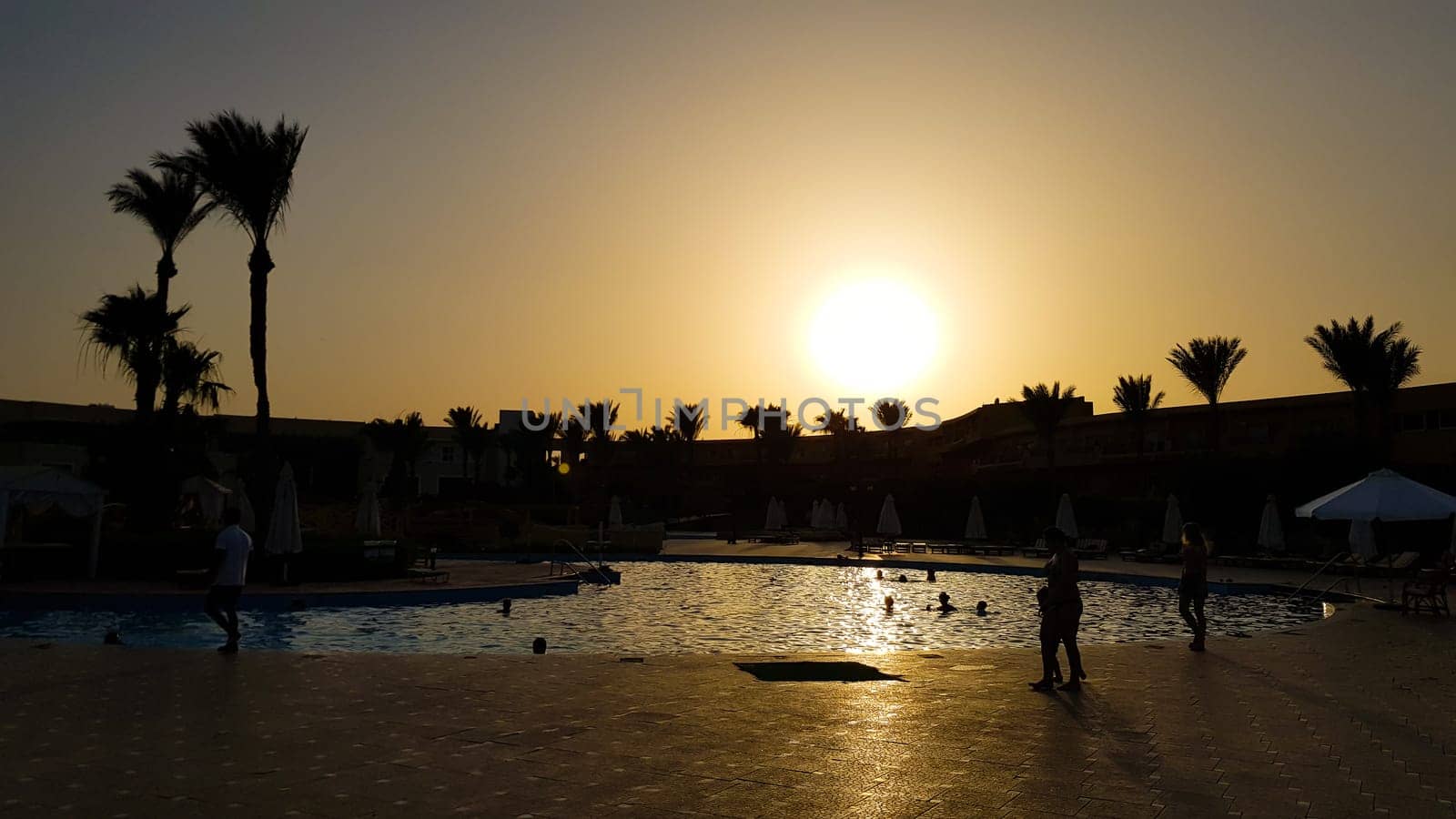 pool at night in one of the hotels near the beach. Sunset over the pool at the hotel. Infinity pool at dusk. Silhouette moment over beach side.