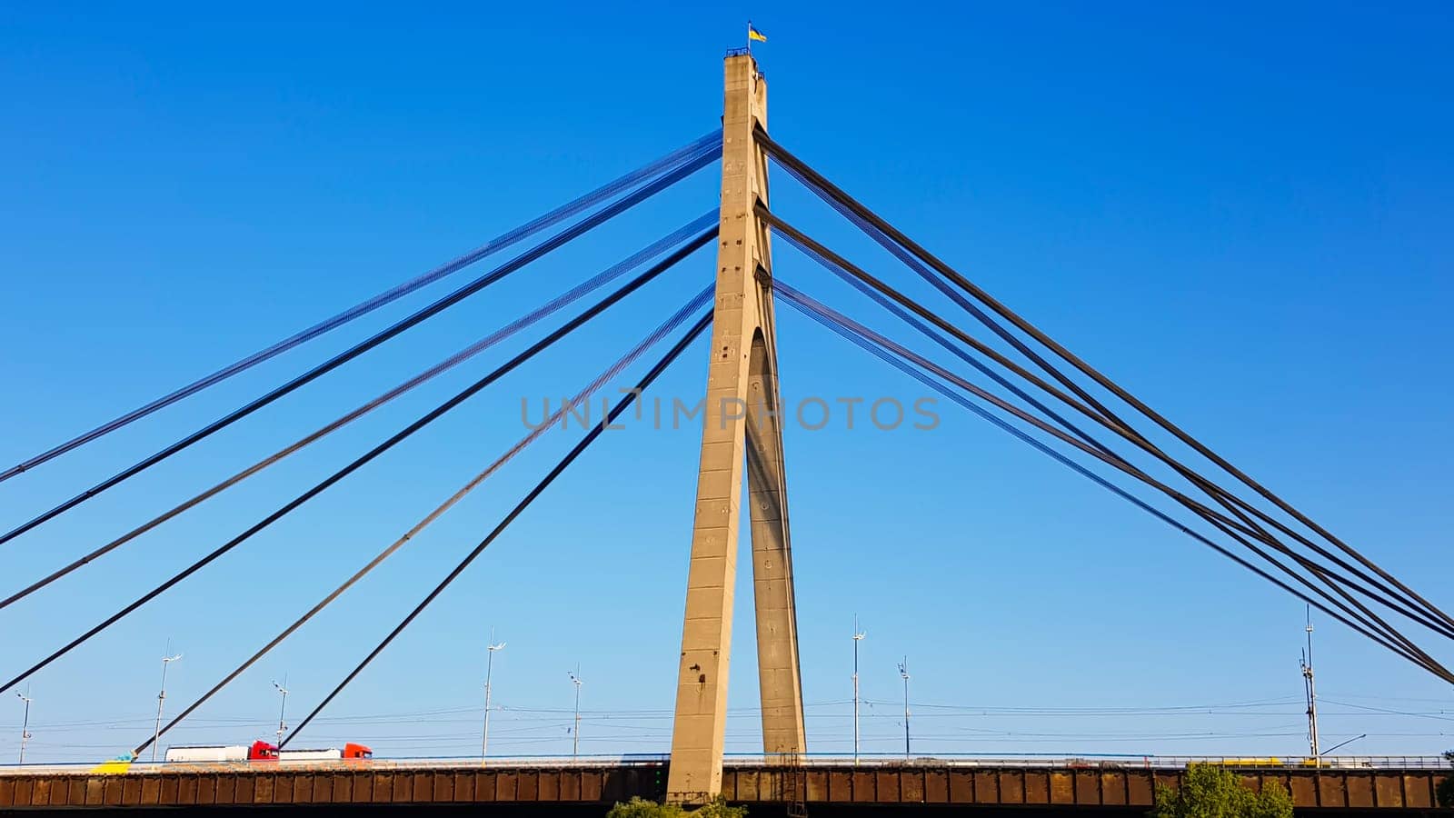 Ukraine, Kiev - August 20, 2019: A bridge across the river with pulling ropes. North bridge against the backdrop of a beautiful simple blue sky without clouds in Kiev. R. Dnieper. Ukraine. Scenery