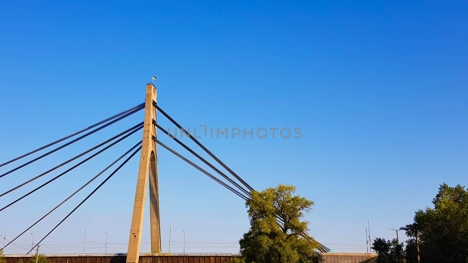 Ukraine, Kiev - August 20, 2019: A bridge across the river with pulling ropes. North bridge against the backdrop of a beautiful simple blue sky without clouds in Kiev. R. Dnieper. Ukraine. Scenery