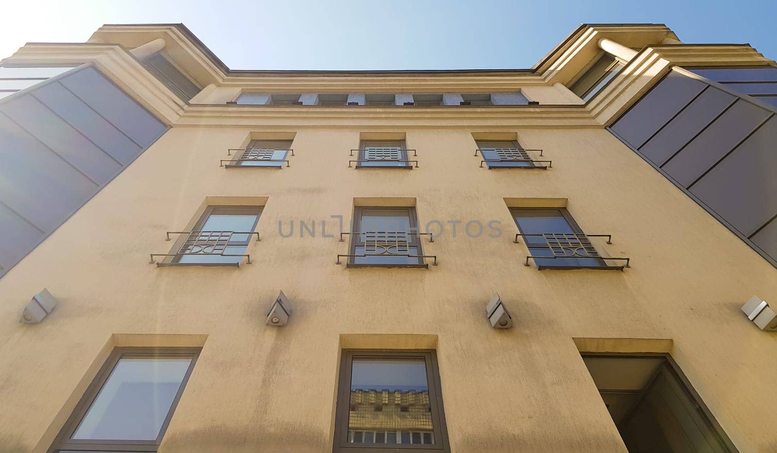 Ukraine, Kiev - August 20, 2019: A tall brown building with windows in the sun and shadow under a blue sky and white clouds. Photo taken from bottom to top