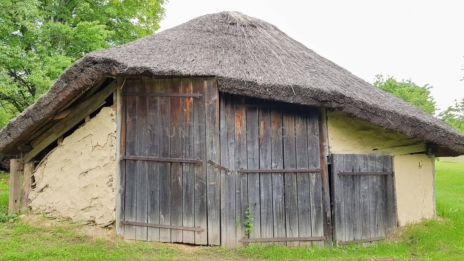 Ukraine, Kiev - June 11, 2020. Old peasant Ukrainian house or barn in the summer with a thatched roof in the village. Pirogovo Museum in the open air of different regions of Ukraine