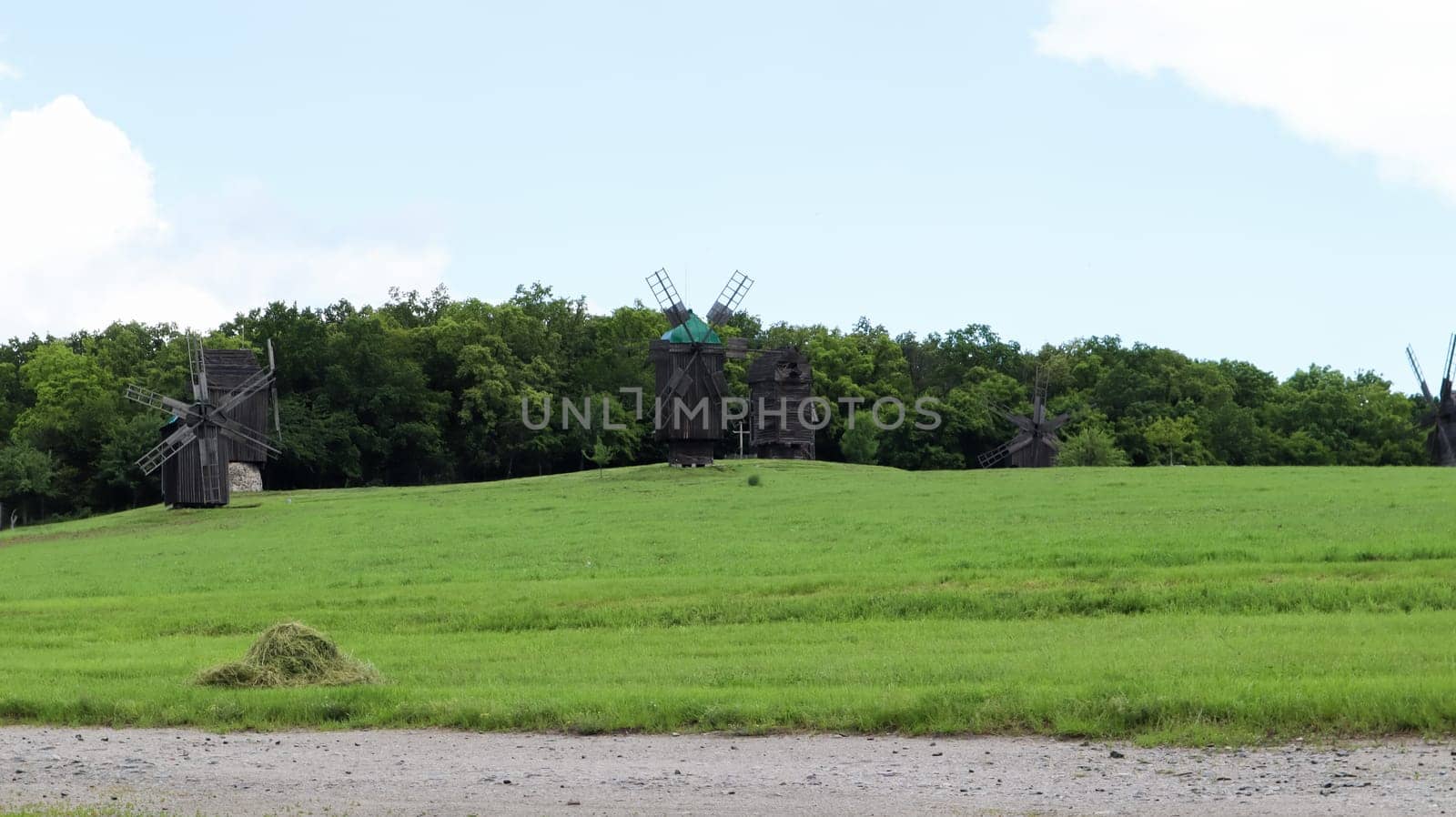 Ukraine, Kiev - June 11, 2020. Old Ukrainian wooden windmills of the XIX century. Summer outdoor landscape. Open-air museum of folk architecture and life, Pirogovo, Ukraine. Tourism and travel