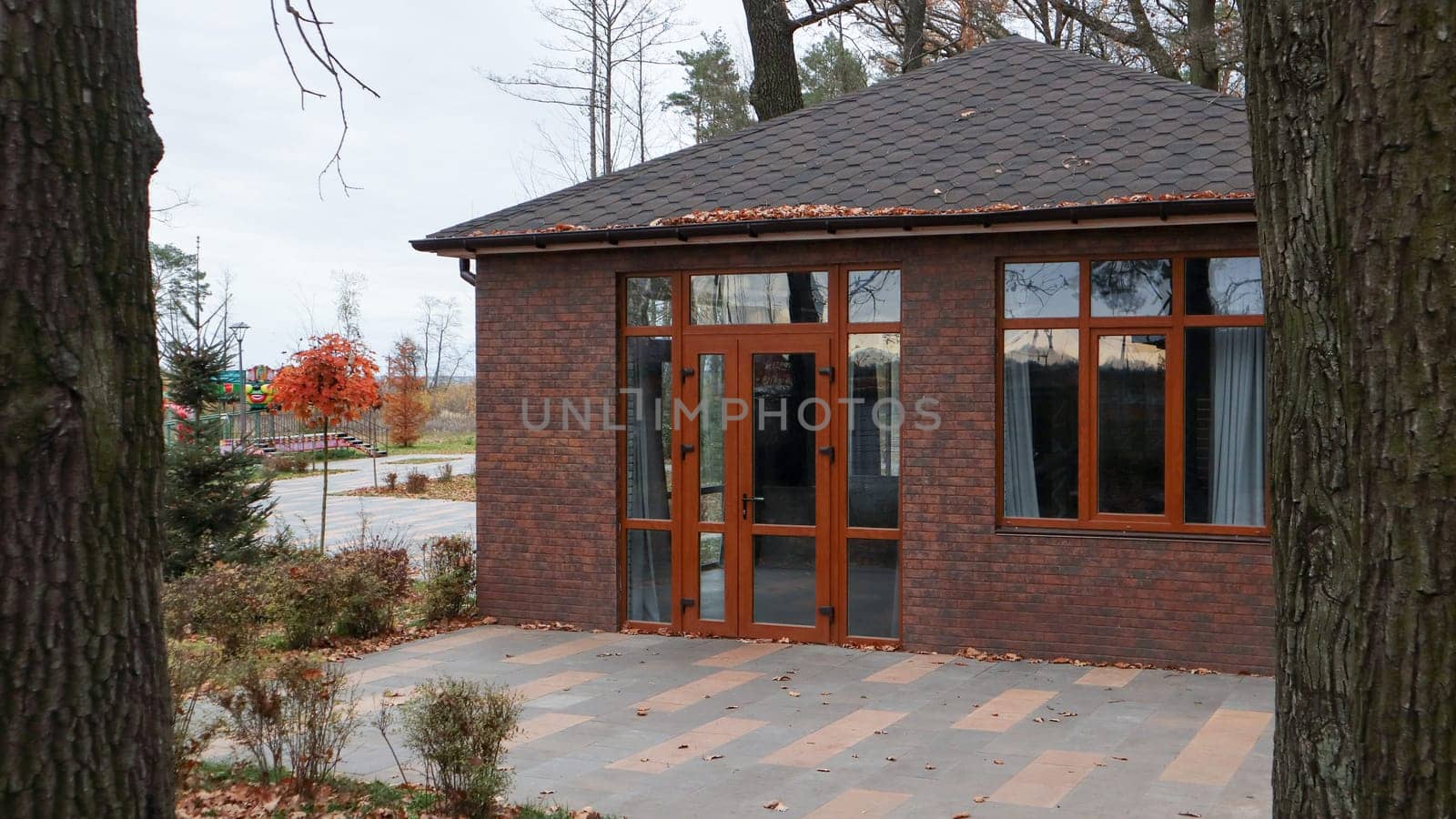 Ukraine, Bucha - October 20, 2019: a large stylish house made of brown stone, large windows and a huge courtyard with trees. Beautiful brick house in the autumn forest. European village house