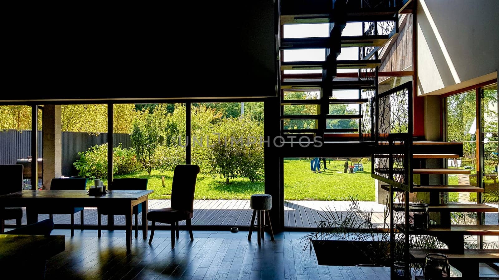 Ukraine, Kiev - September 24, 2019: Luxurious house with large windows in a private garden. There is no one inside. Bright interior of a loft kitchen with furniture, stairs, stained glass windows, wooden floor