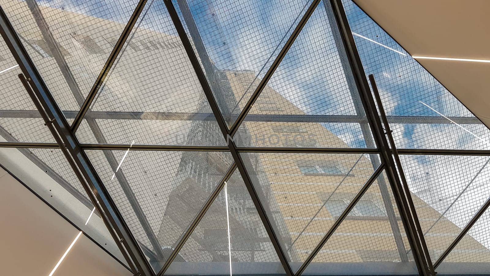 Ukraine, Kiev - September 24, 2019: Structural glazing of the facade. Abstract background with glass ceiling elements in a modern building. view of the blue sky through a glass window, separated by lattice elements