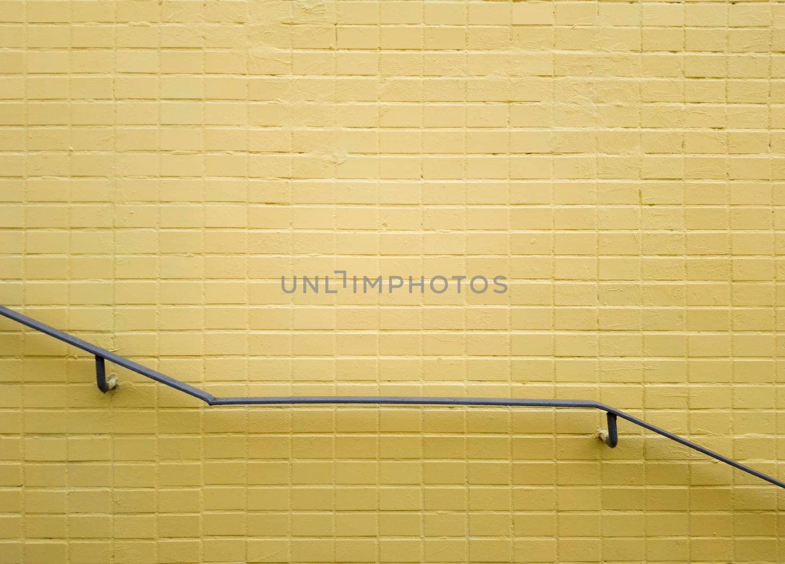 Railings of gray metal near a yellow brick wall. Yellow background, brick texture. Minimalism. Copy space.