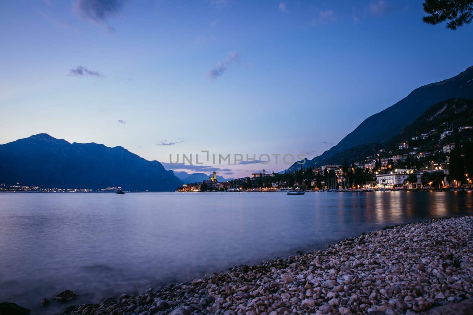 Beautiful evening scenery on the beach with cute little village, lago di garda, Italy.