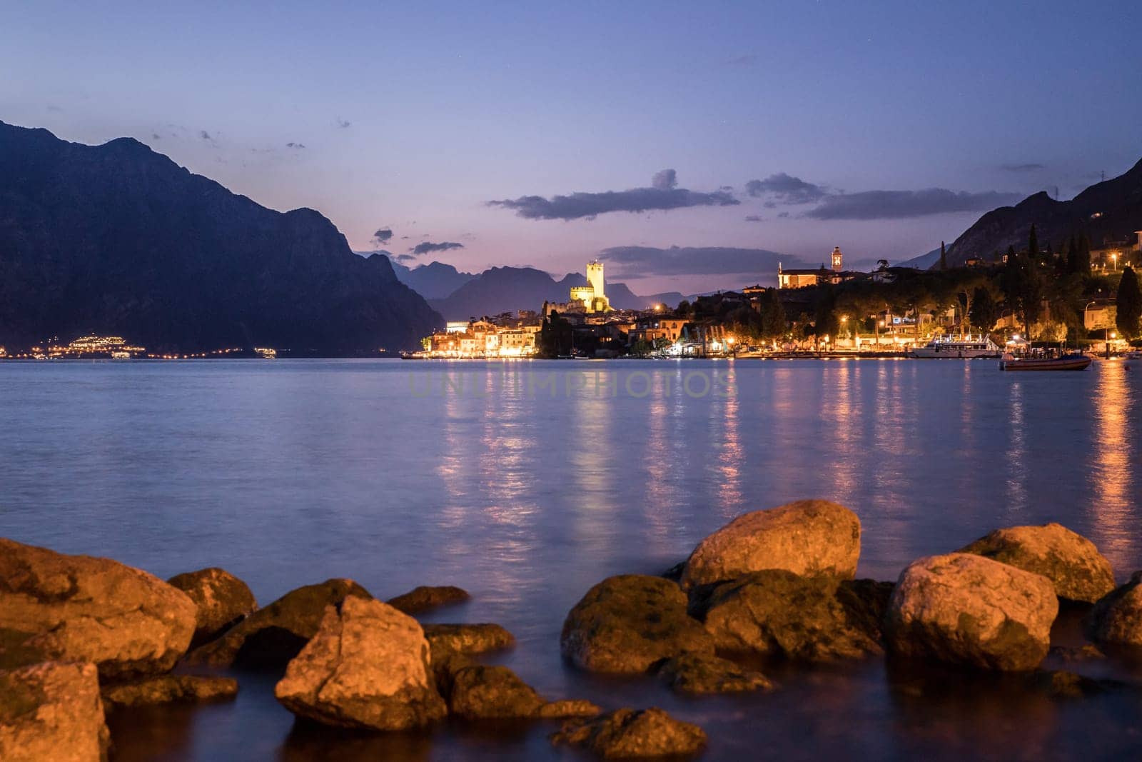 Beautiful night  scenery with cute little village, lago di garda, Italy. Stones in the foreground.