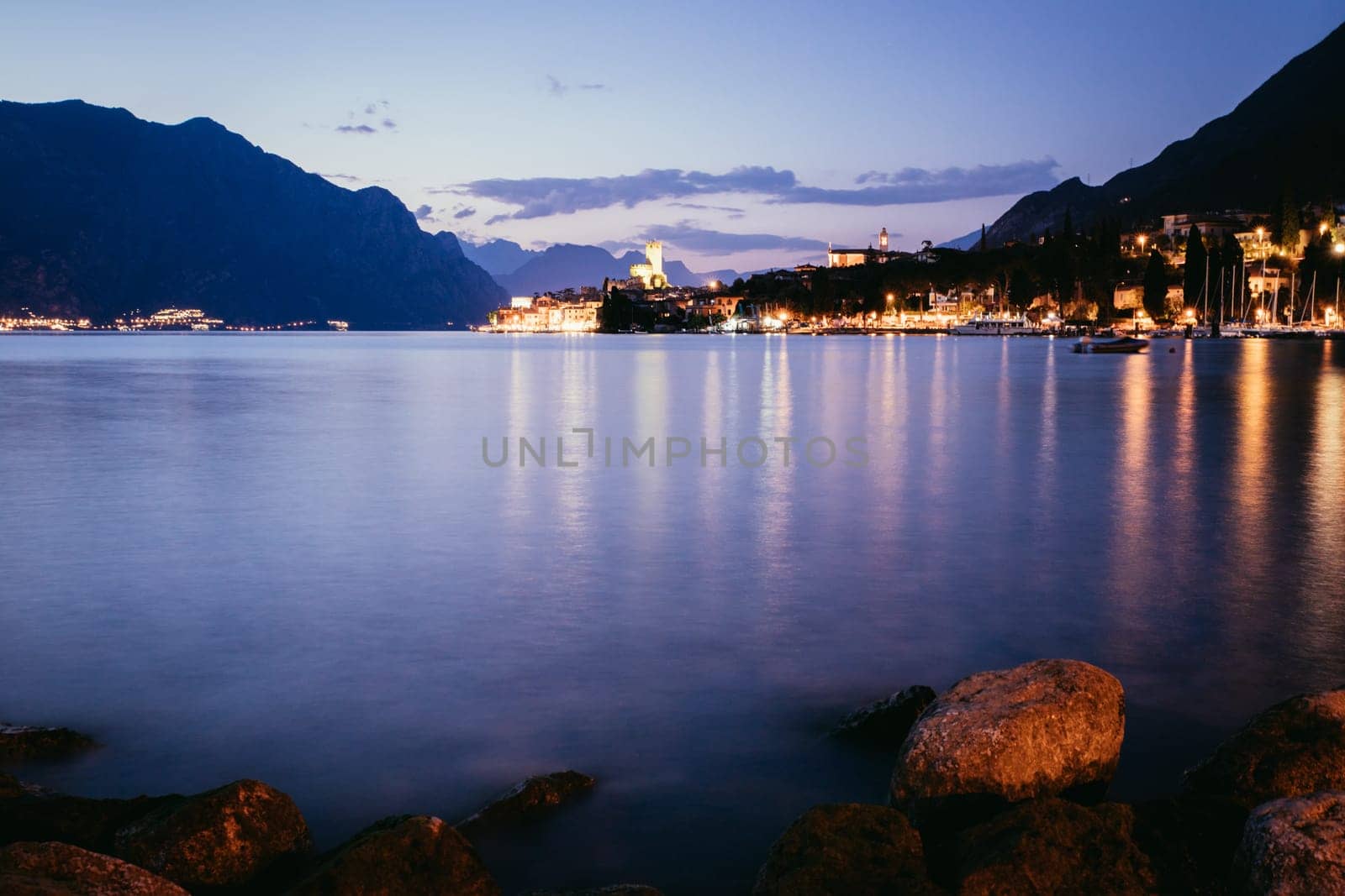 Beautiful night  scenery with cute little village, lago di garda, Italy. Stones in the foreground.