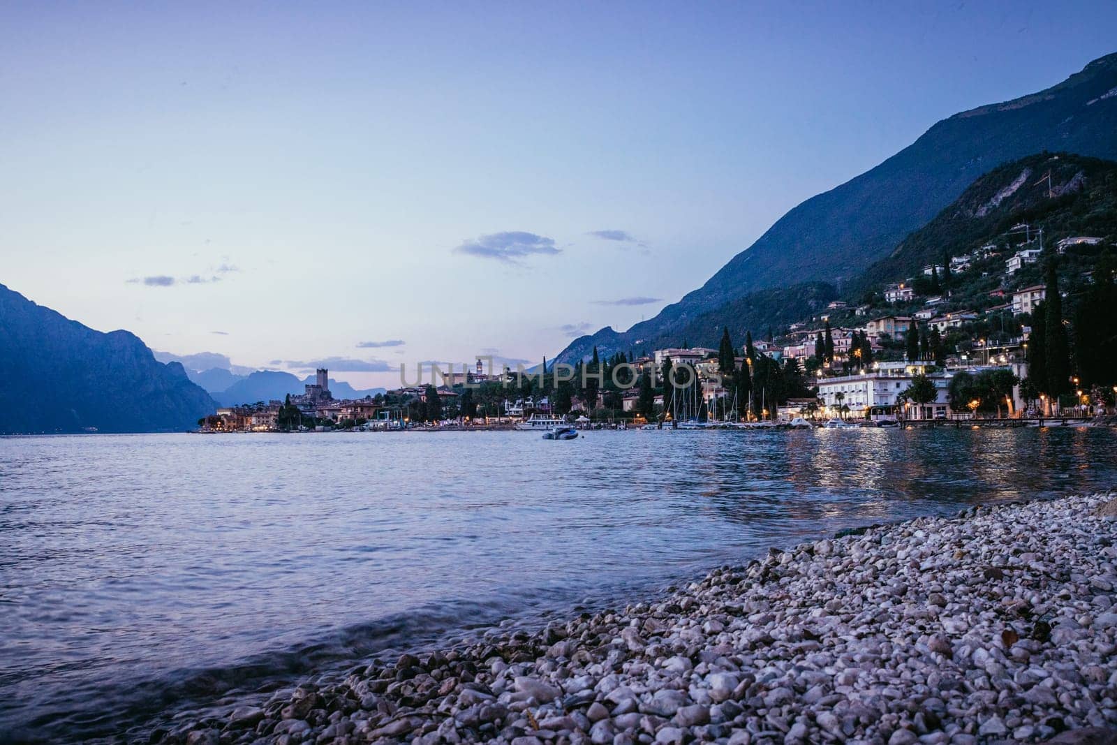 Beautiful evening scenery on the beach with cute little village, lago di garda, Italy.