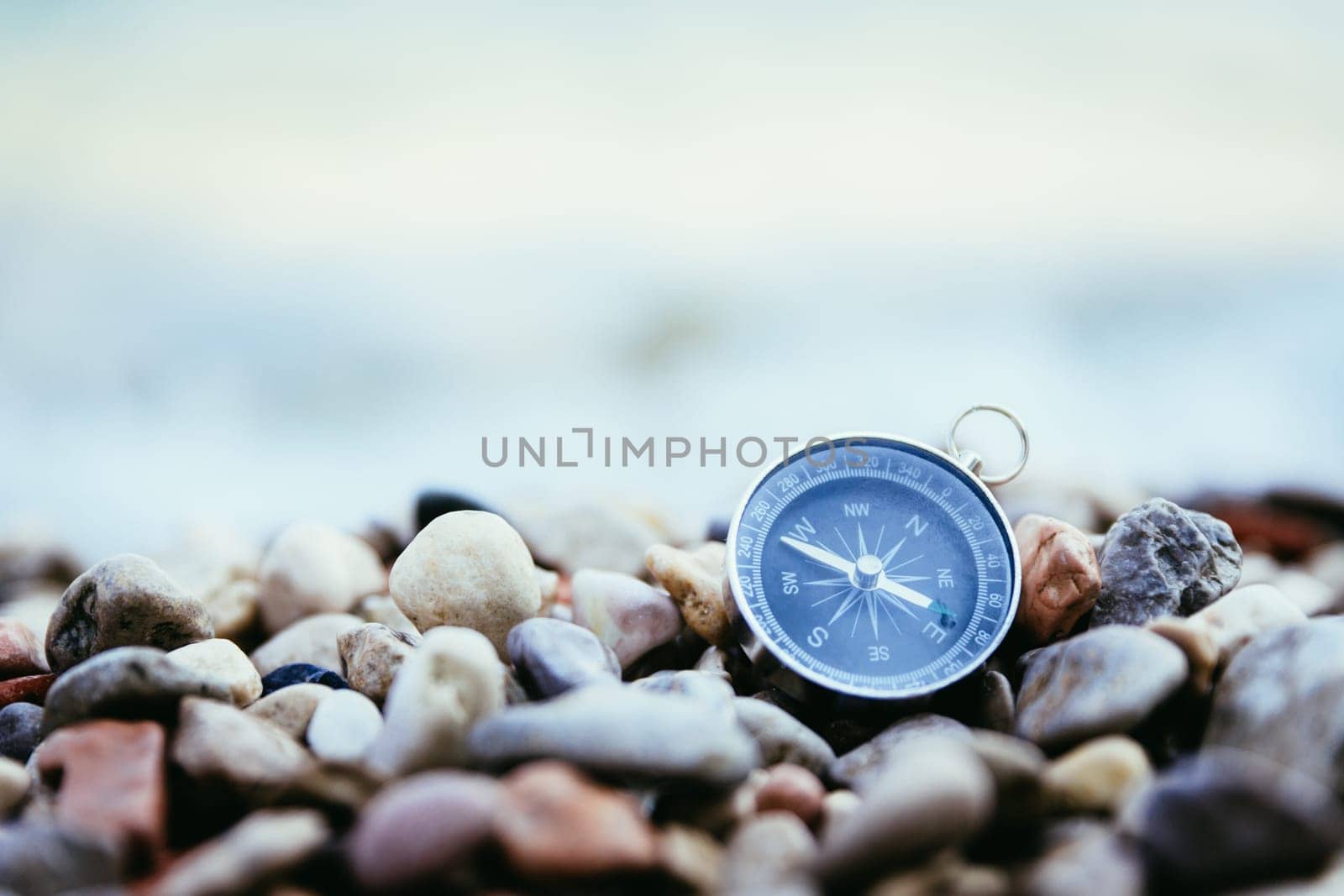 Compass on the beach, small stones, text space