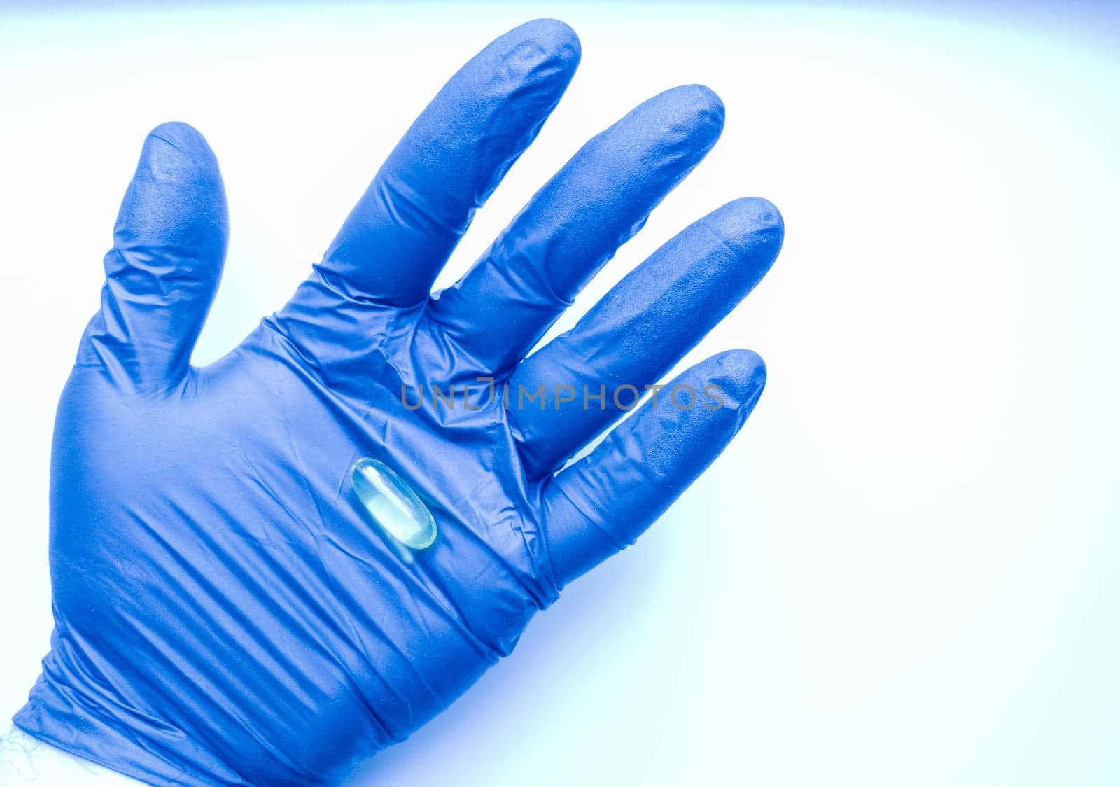 The doctor holds medicines, pills, pills, omega-3 vitamins, capsules with fish oil, a hand in blue gloves. Drug combination therapy for diseases. Capsules on a researcher's hand with a blue glove