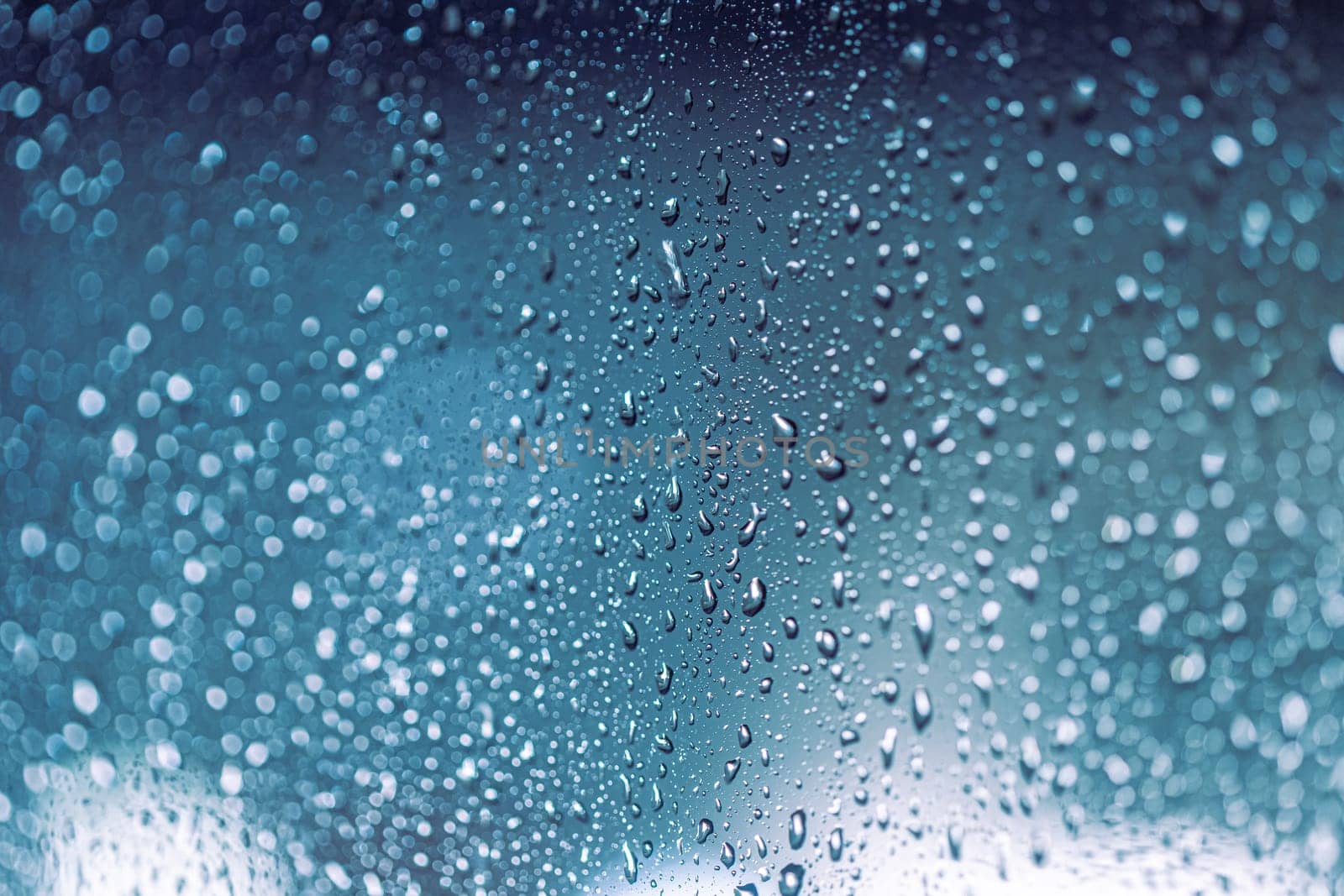Close up of rain drops on the window in rainy night, cool lights