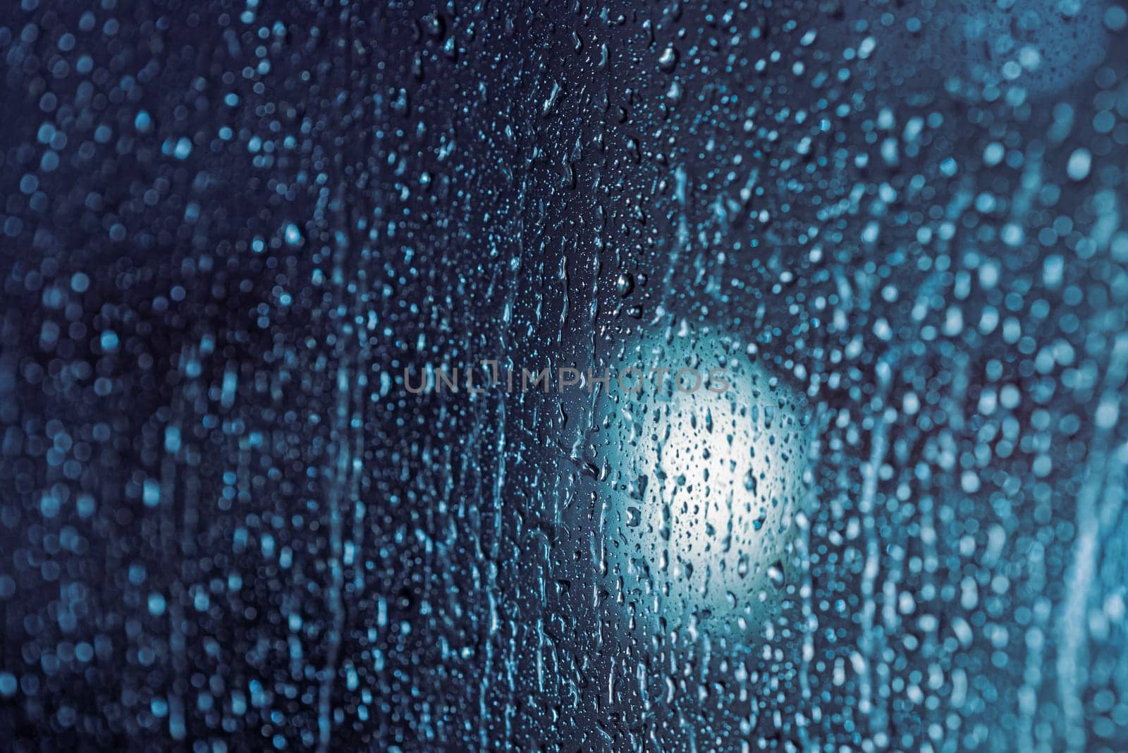 Close up of rain drops on the window in rainy night, cool lights