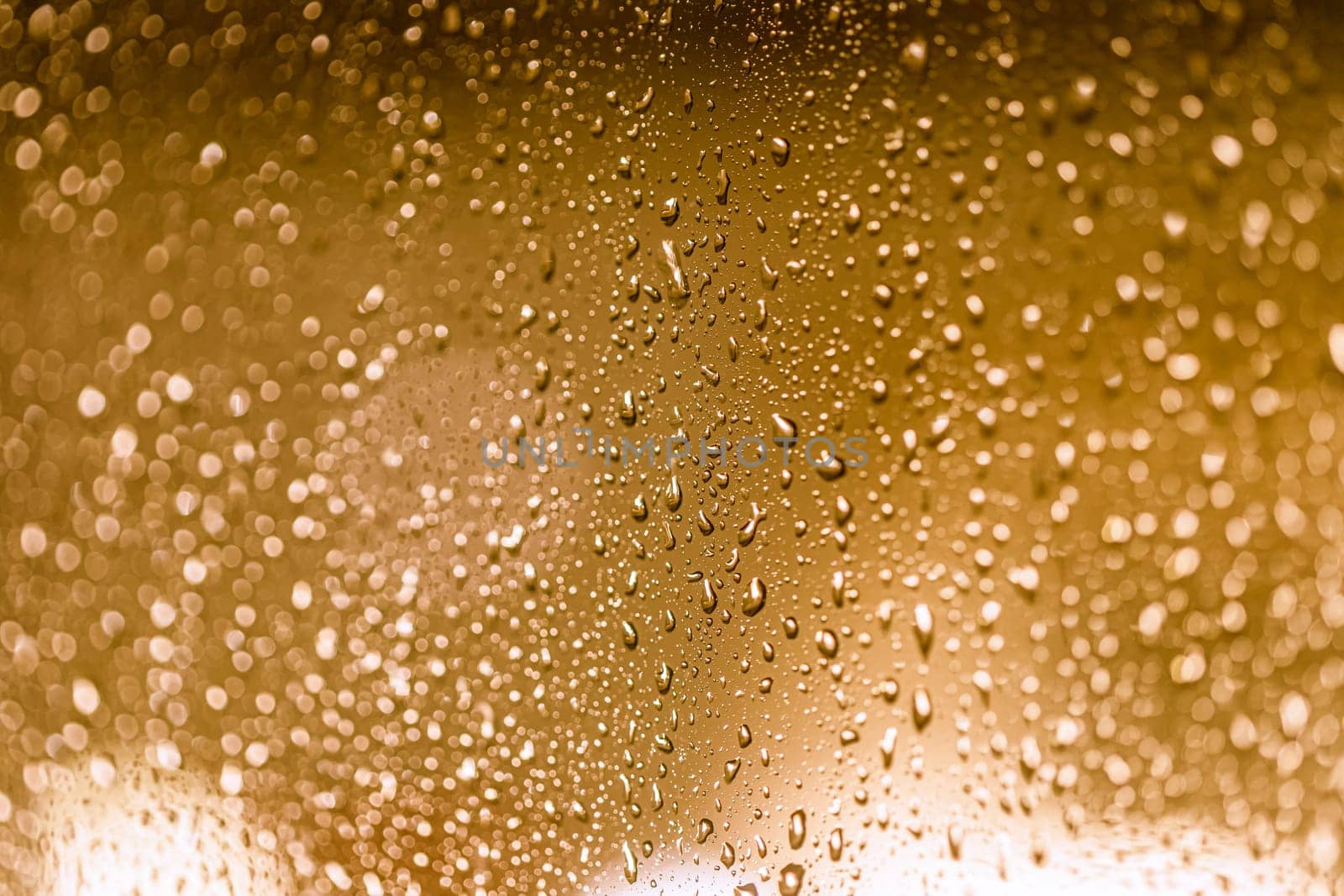 Close up of rain drops on the window in rainy night, warm lights