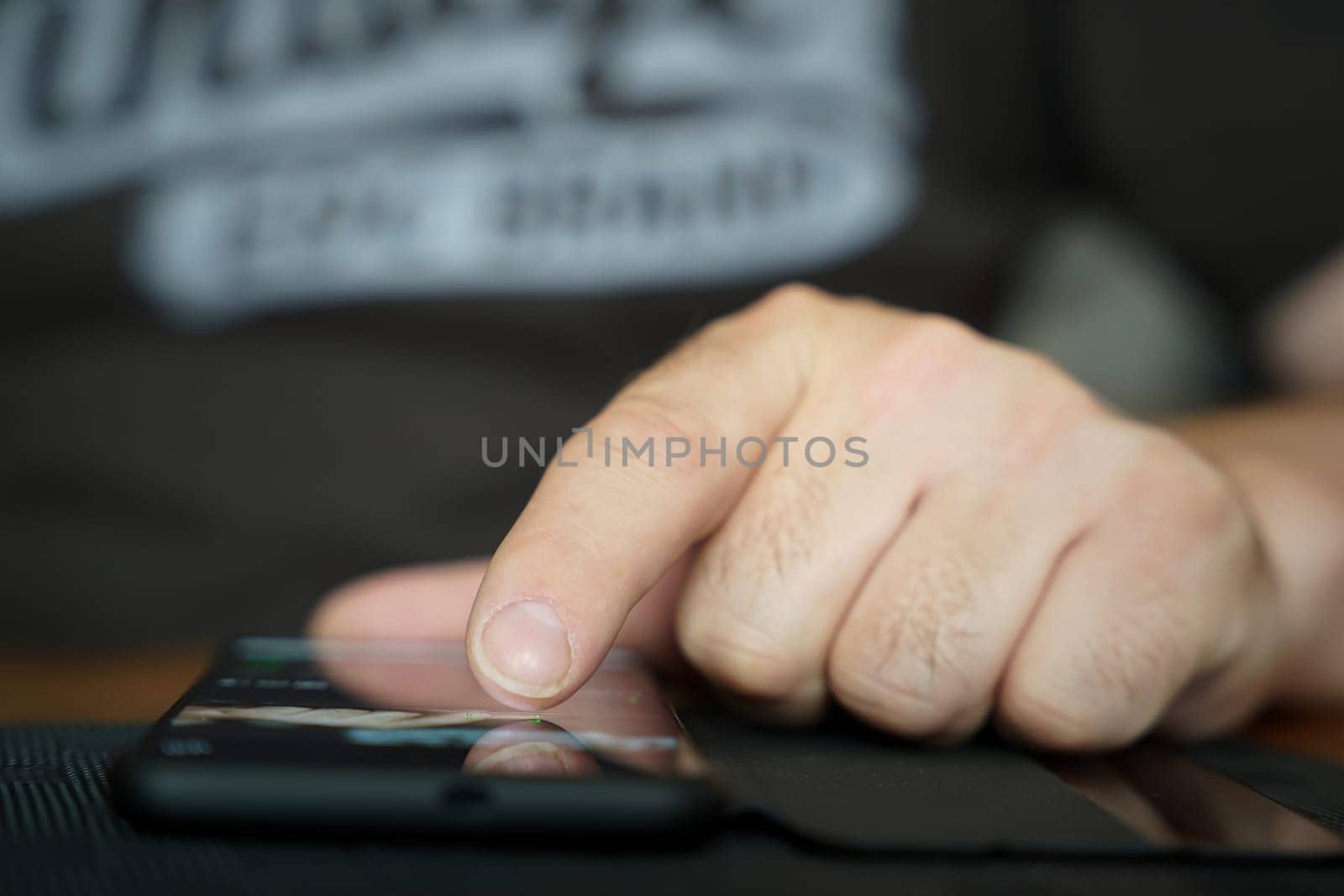Fingers of a person operate a smartphone lying on the table