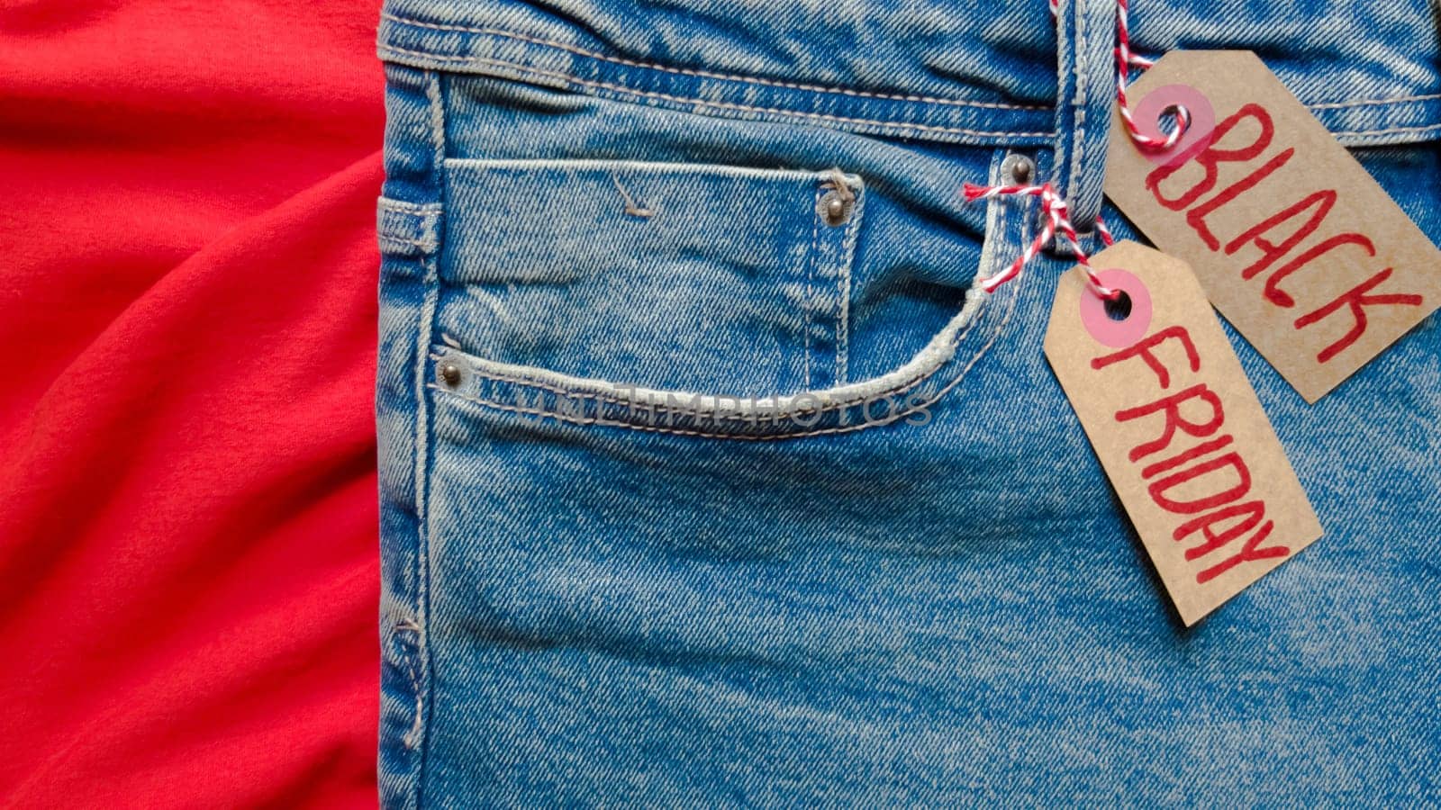Stylish jeans with a black friday flag. Black friday and cyber monday sale discount concept tag with blue jeans. Black friday written on grunge jeans texture. Background, holiday concept. Black Friday - International day of shopping, promotions, discounts, sales. The sales season is the fourth Thursday of November. Copy space, place for text, flat lay.