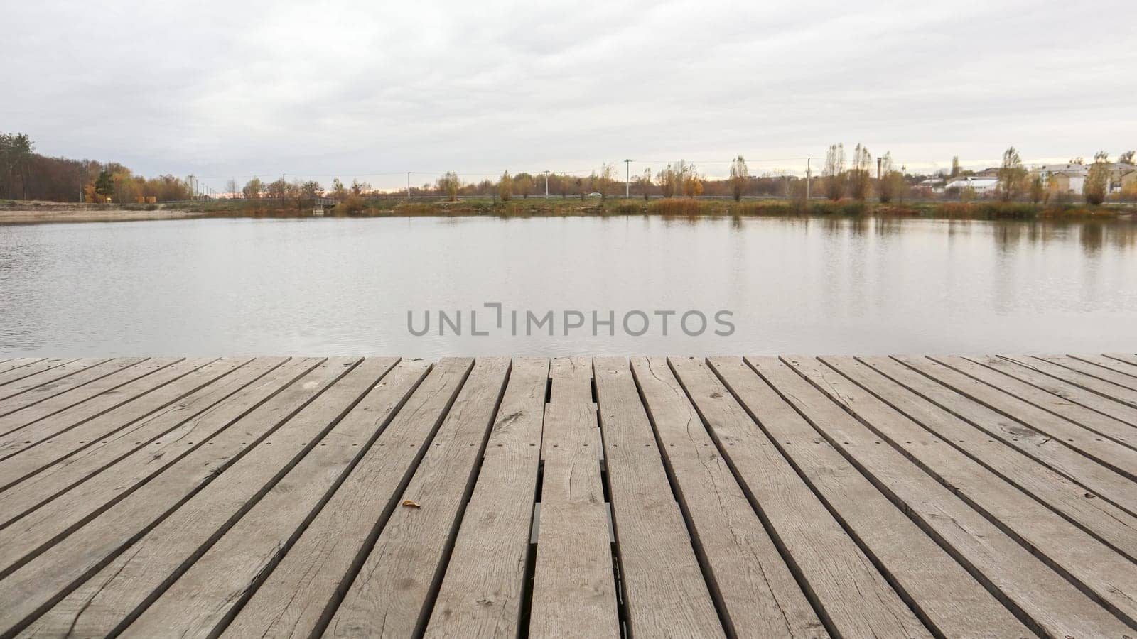 A small wooden pier on a quiet lake in the autumn foggy morning