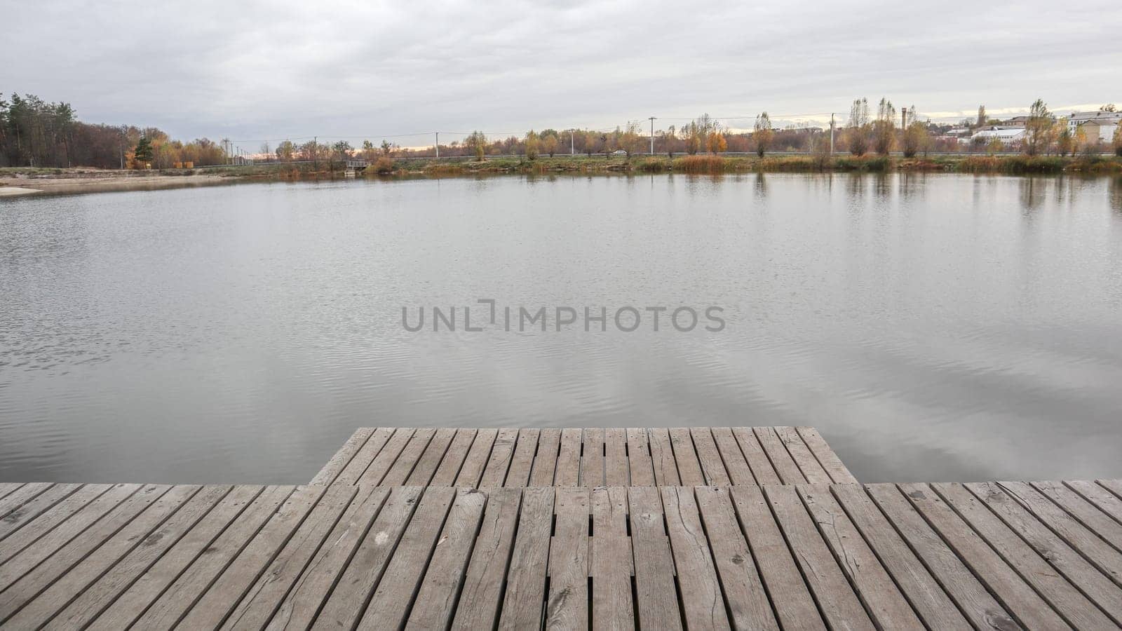 A small wooden pier on a quiet lake in the autumn foggy morning