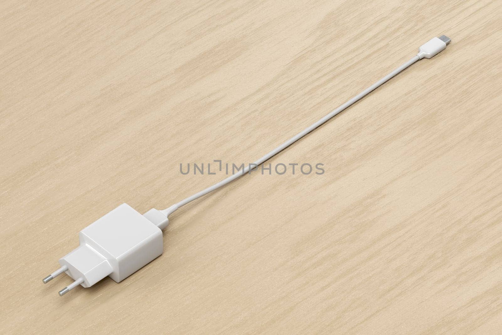 Smartphone power adapter with USB-C cable on wooden desk