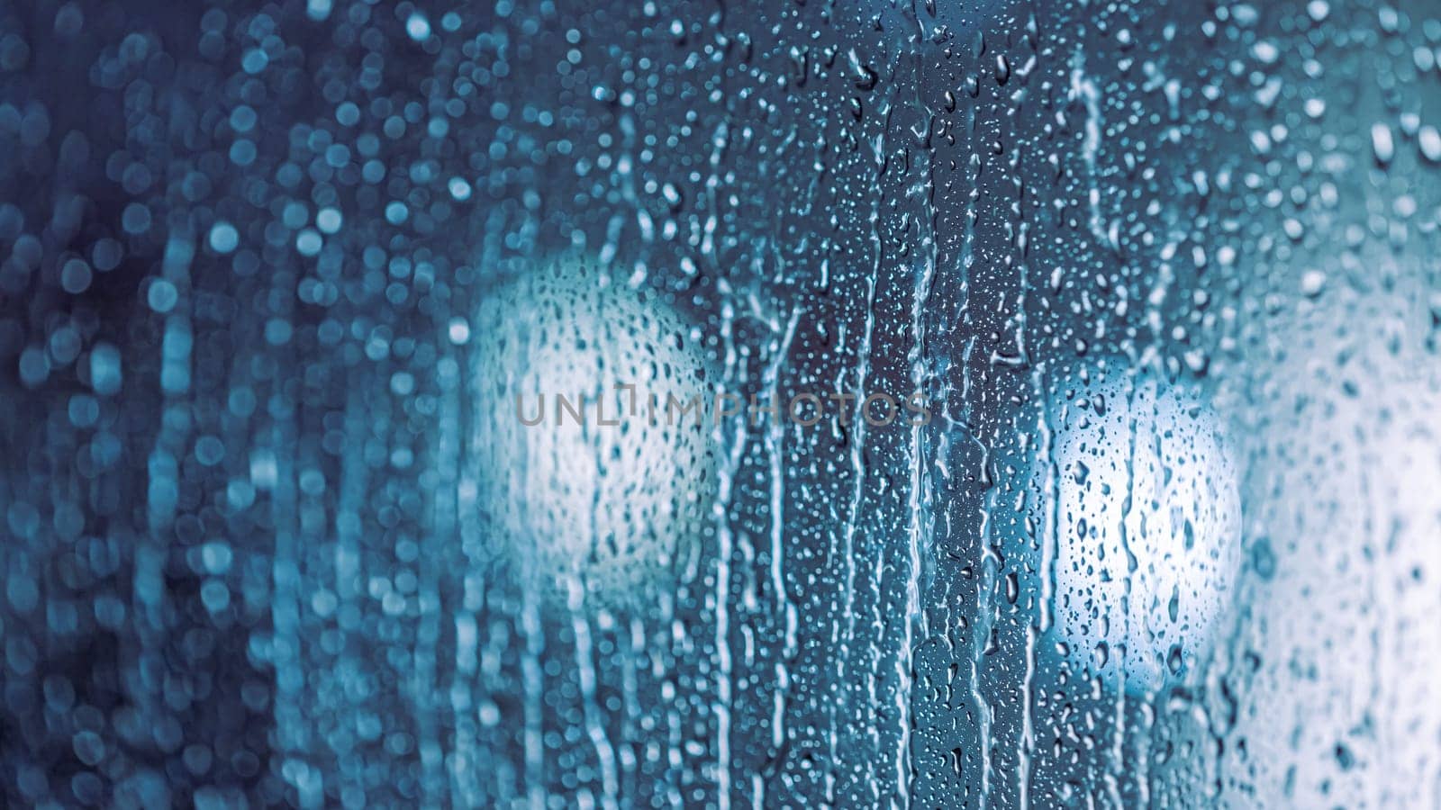 Close up of rain drops on the window in rainy night, cool lights