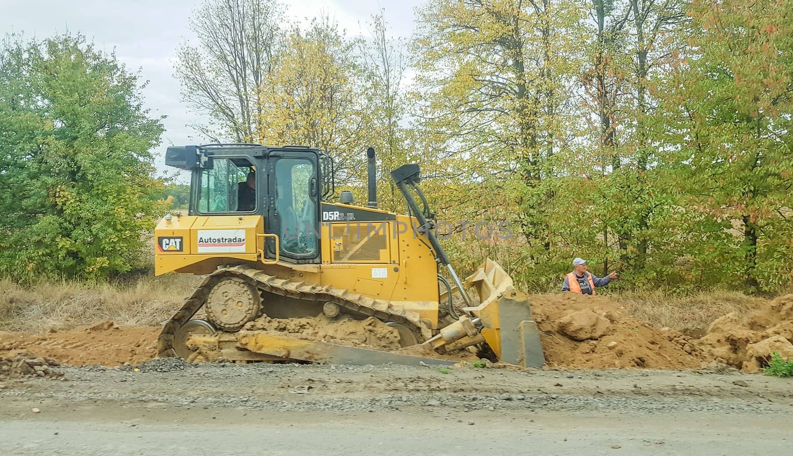 Ukraine, Kiev - October 1, 2019: Road roller, tractor and construction equipment are working on a new road construction site. The road is closed for road repair, route extension, pothole repair.