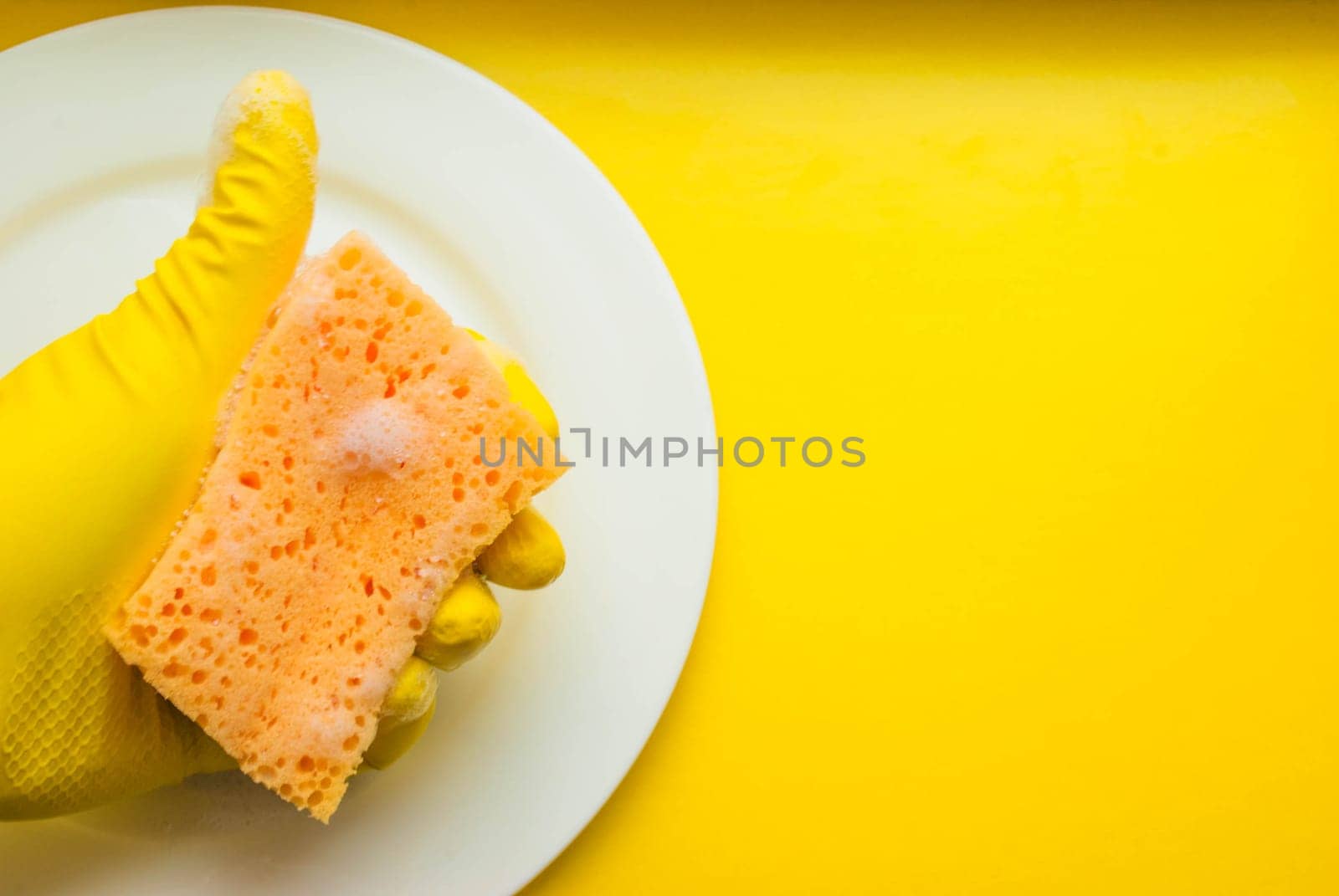 Cleaning sponge on a white plate on a yellow background.