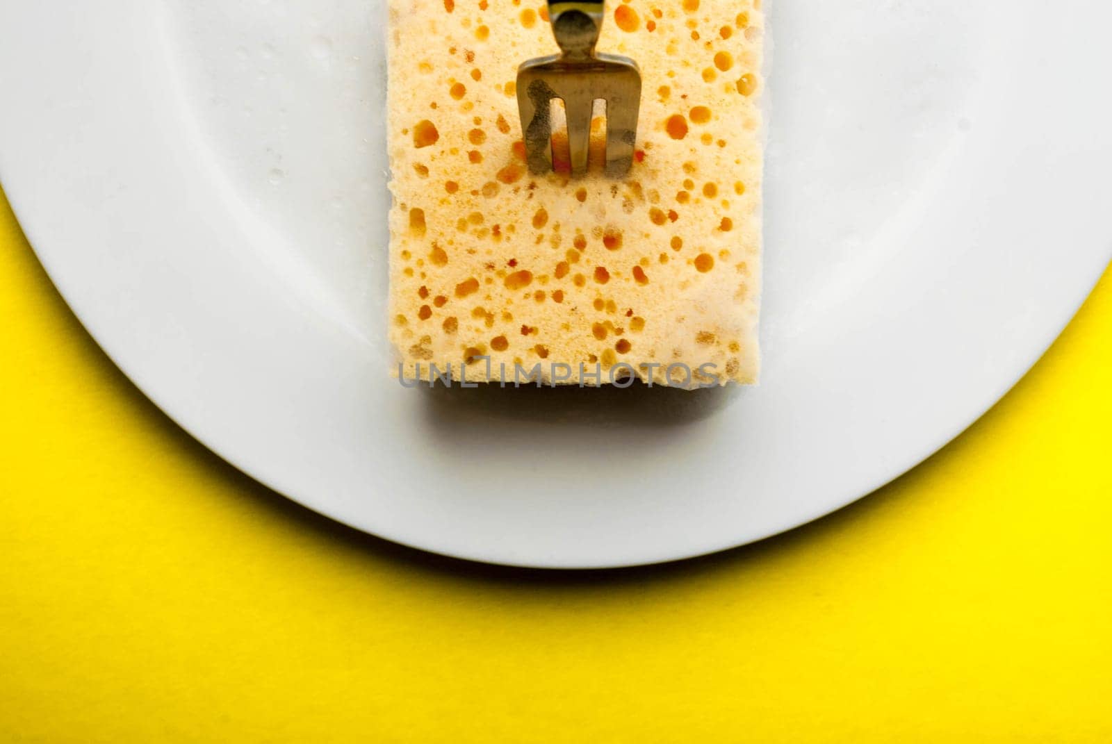 Cleaning sponge on a white plate on a yellow background.