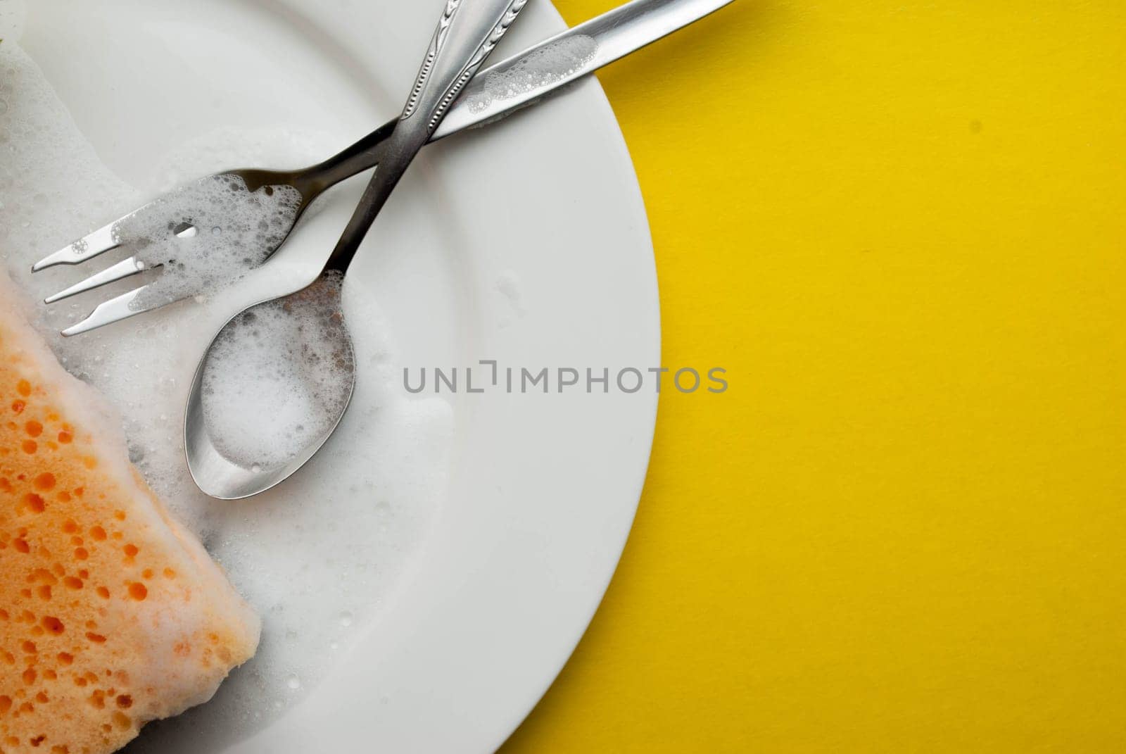 Cleaning sponge on a white plate on a yellow background.