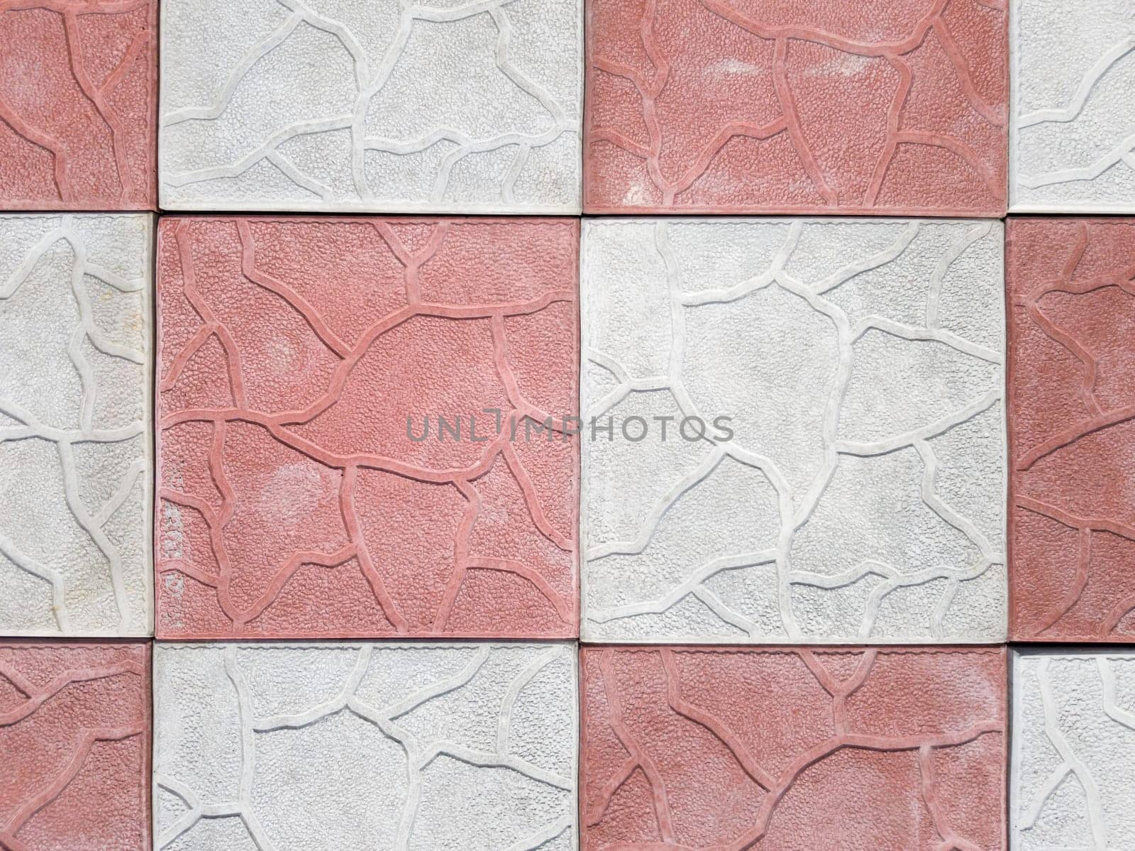 concrete coating of gray and red colors. Sidewalk of gray and pink pavers close-up. Texture, background from curly gray-orange stone. Top view on the sidewalk.