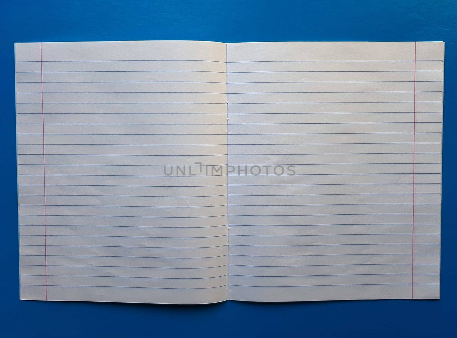 Open notebook on a white lining on a blue wooden tabletop.