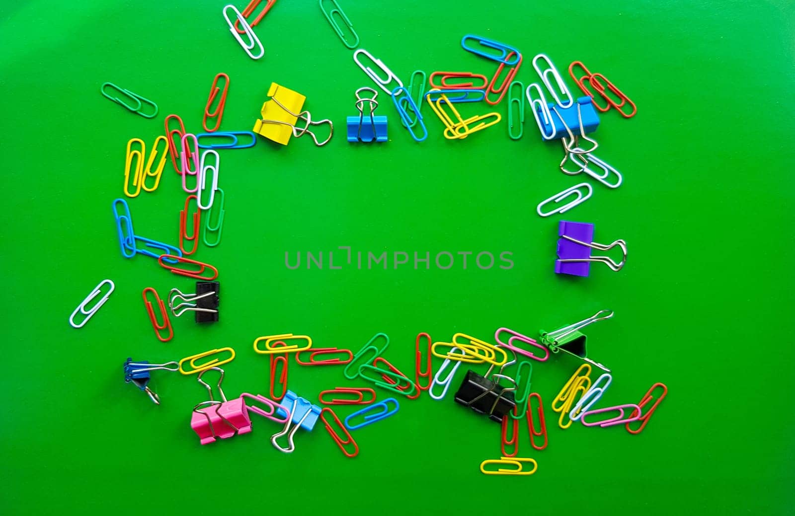 pile of paper clips isolated on green background, documents, office supplies concept, dirty office desk. Empty place for writing and text. Top view, layout. flat lay.