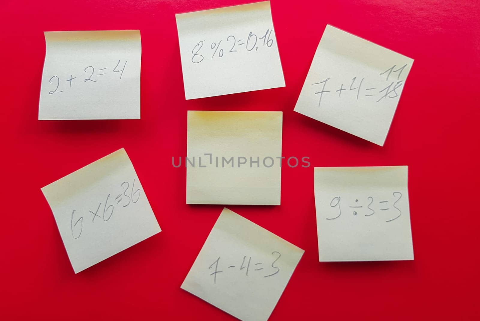 Blank yellow sticky notes with mathematical equations and solving them on a red background, concept of business and study work. Yellow commemorative stickers on the red wall. Layout.