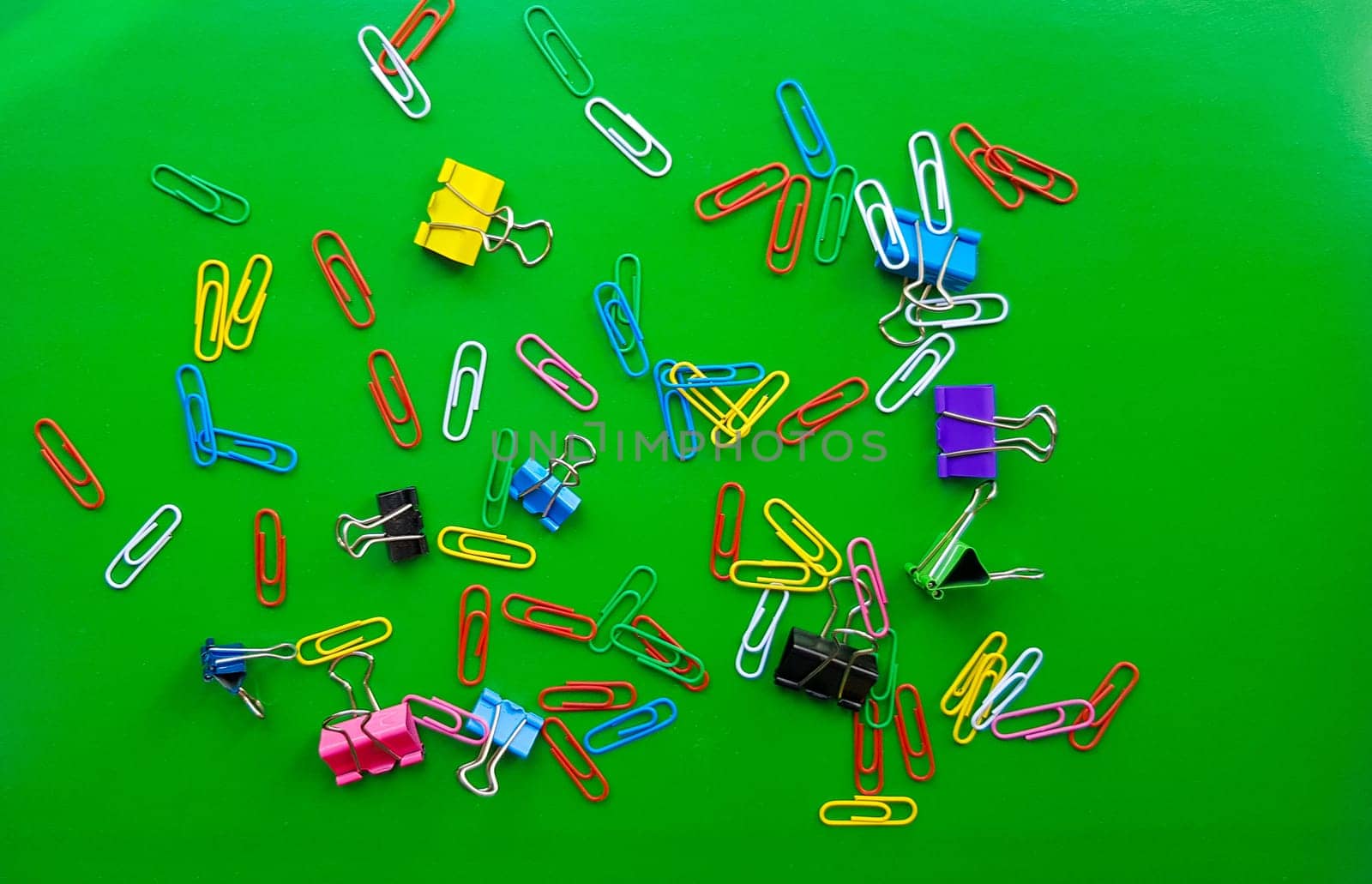 pile of paper clips isolated on green background, documents, office supplies concept, dirty office desk. Empty place for writing and text. Top view, layout. flat lay.