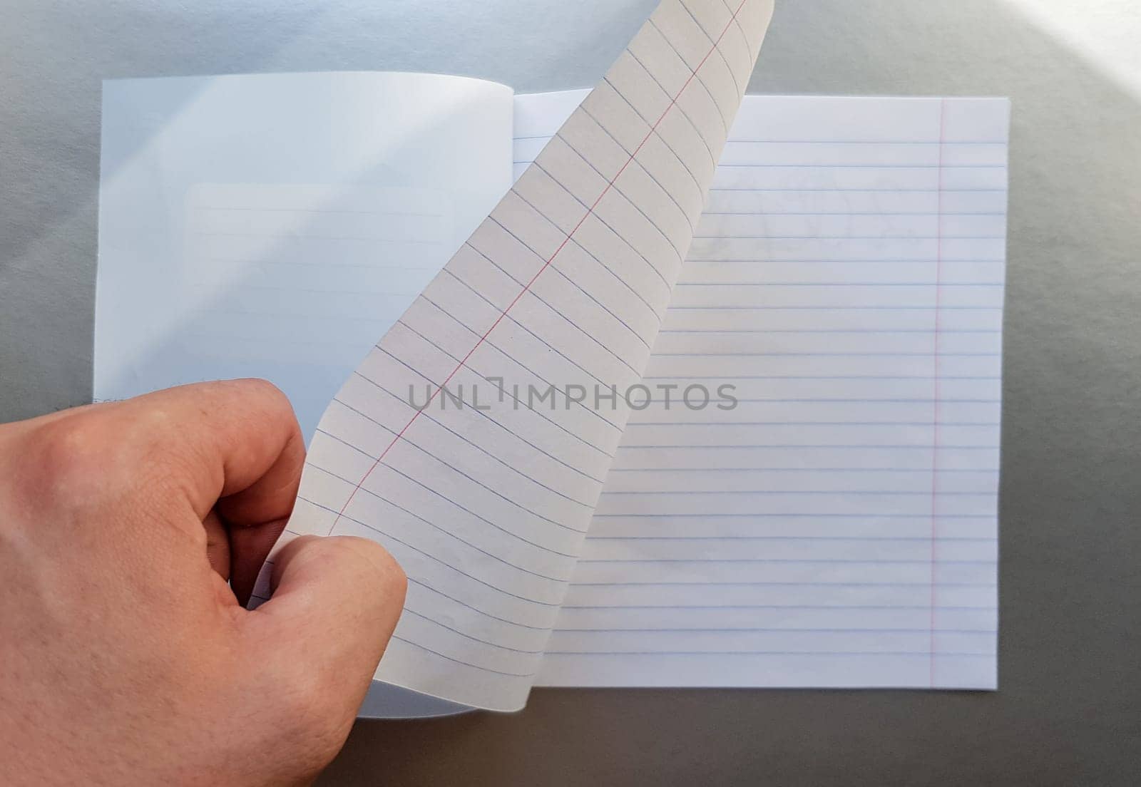 Design concept - Top view of a high quality male hand leafing through a sheet of blue striped notebook. Top view, copy space, flat lay.