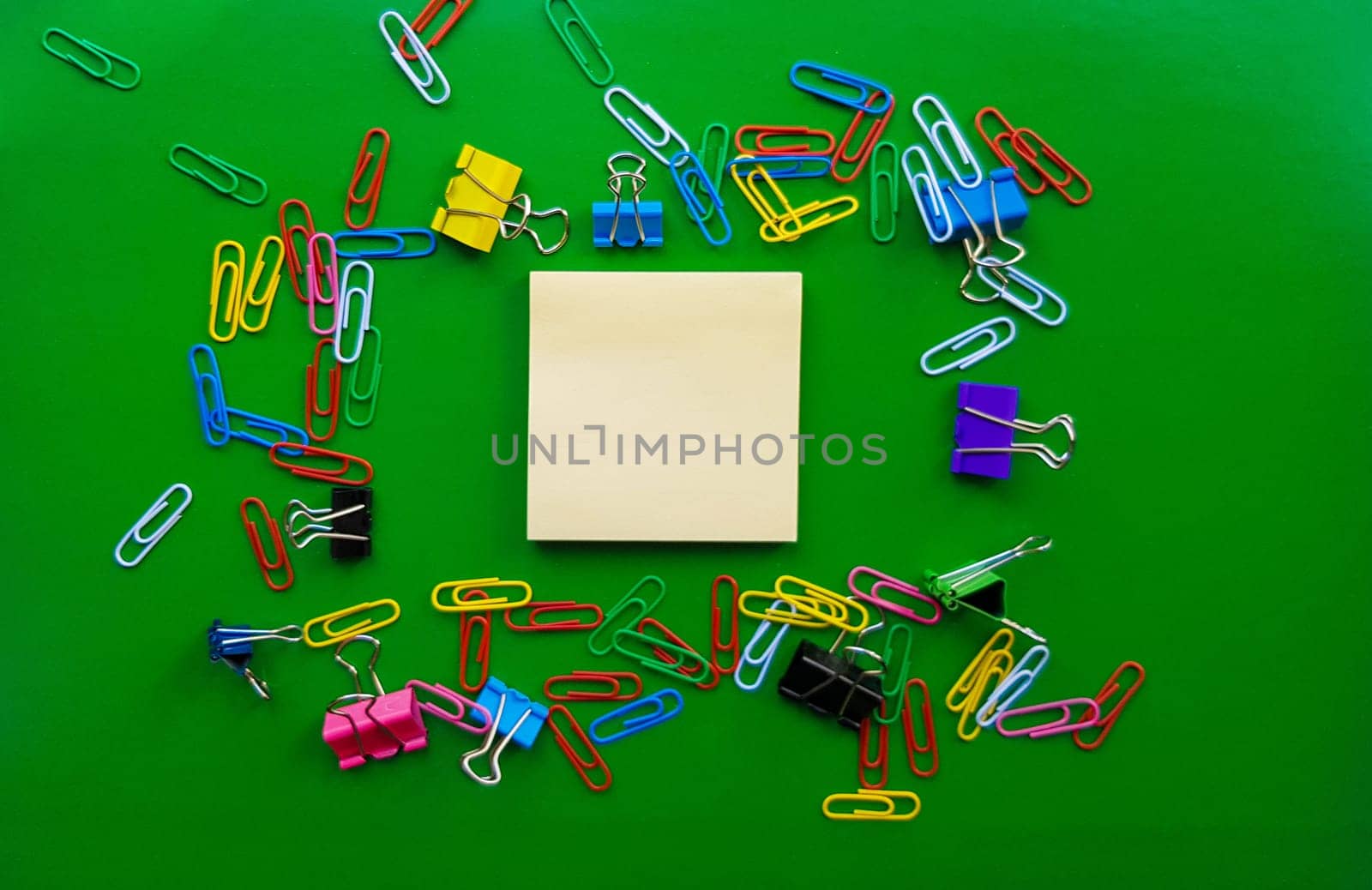 pile of paper clips isolated on green background, documents, office supplies concept, dirty office desk. Empty place for writing and text. Top view, layout. flat lay.
