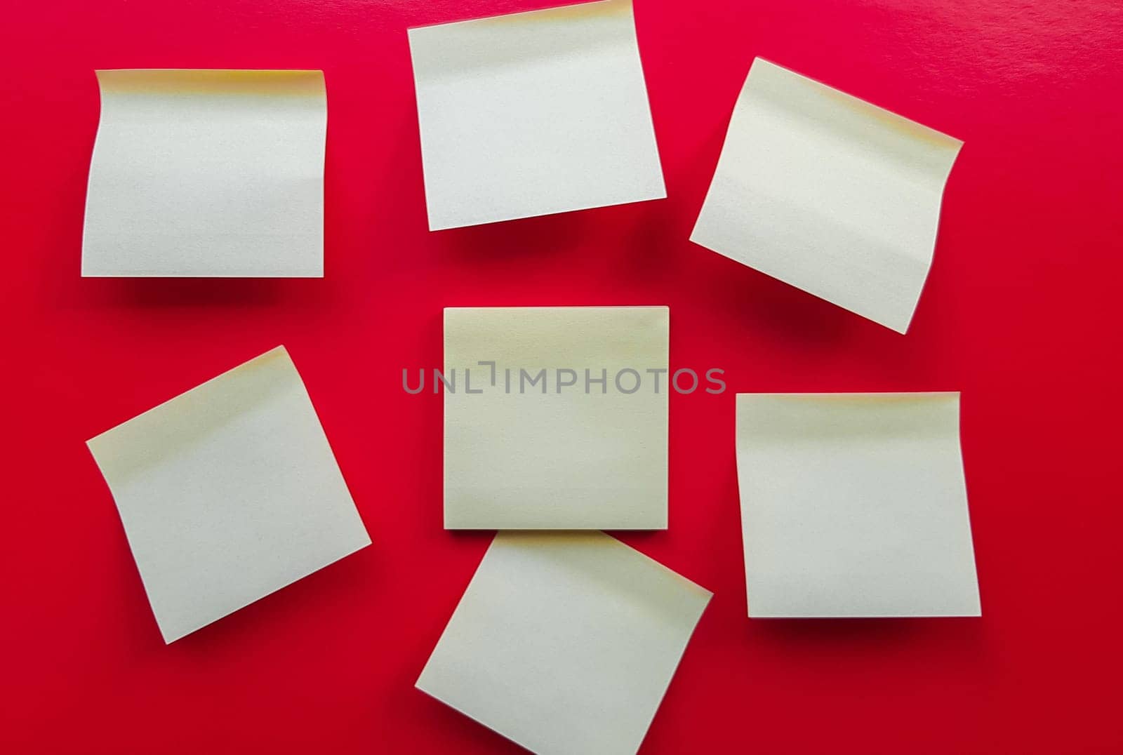 Blank yellow sticky notes on a red background, business work concept. Yellow commemorative stickers on the red wall. Layout.