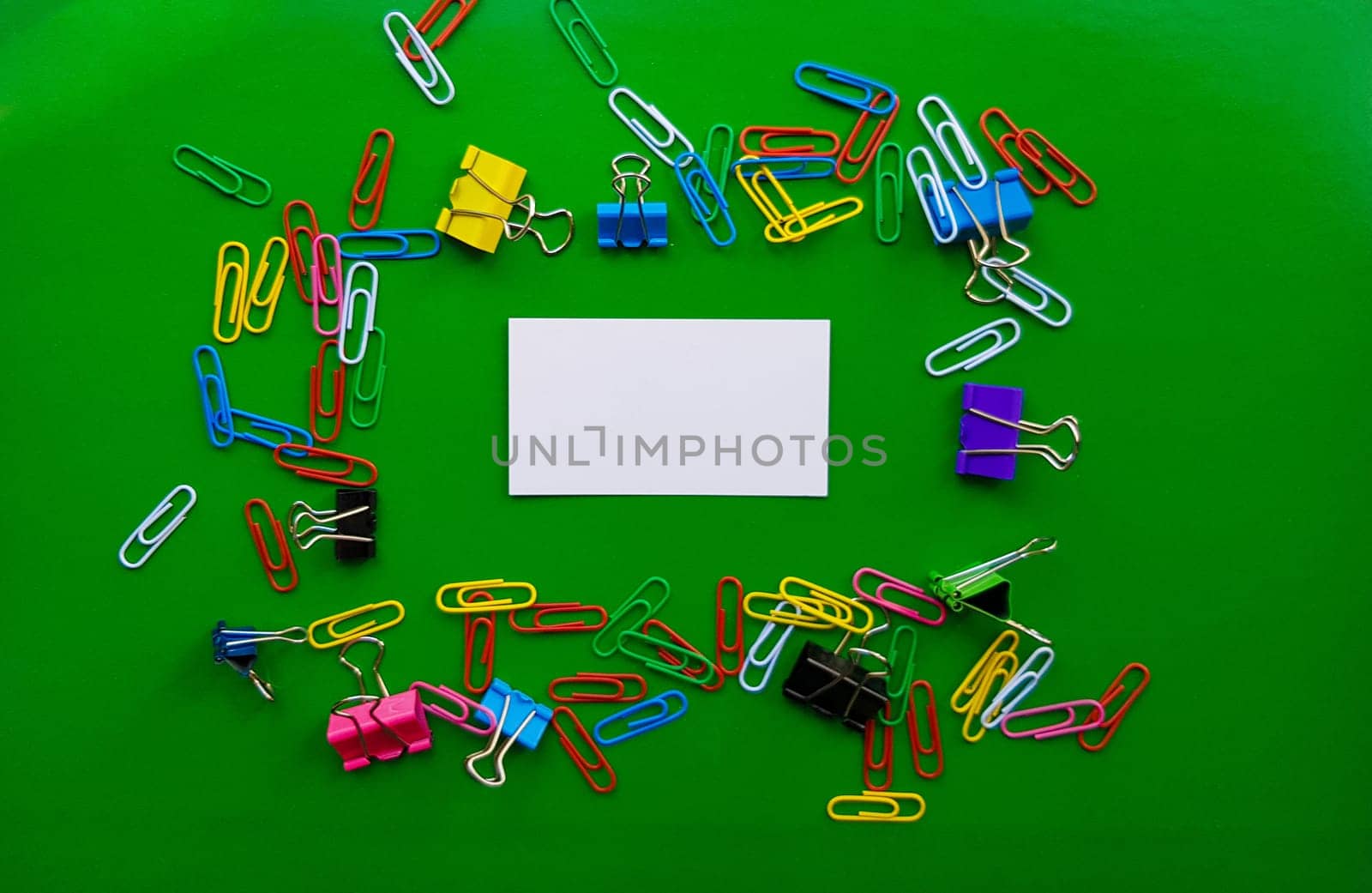 pile of paper clips isolated on green background, documents, office supplies concept, dirty office desk. Empty place for writing and text. Top view, layout. flat lay.