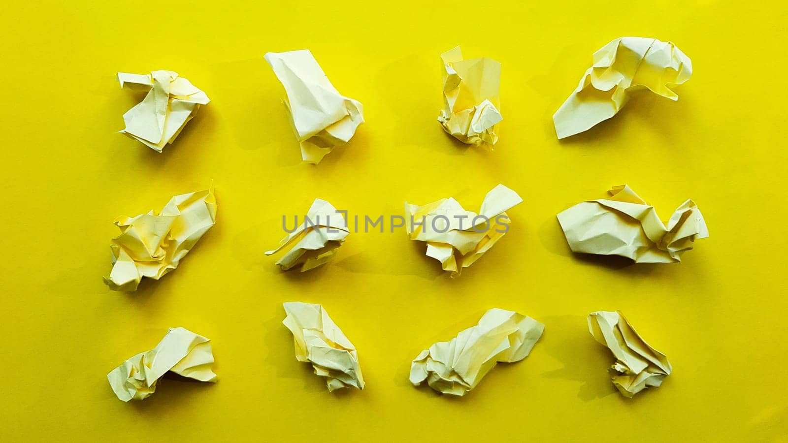 Ball crumpled paper ball isolated on a yellow background. Crumpled paper for texture. Crumpled paper after a brainstorming was thrown into the bin. A piece of yellow crumpled paper on a yellow background
