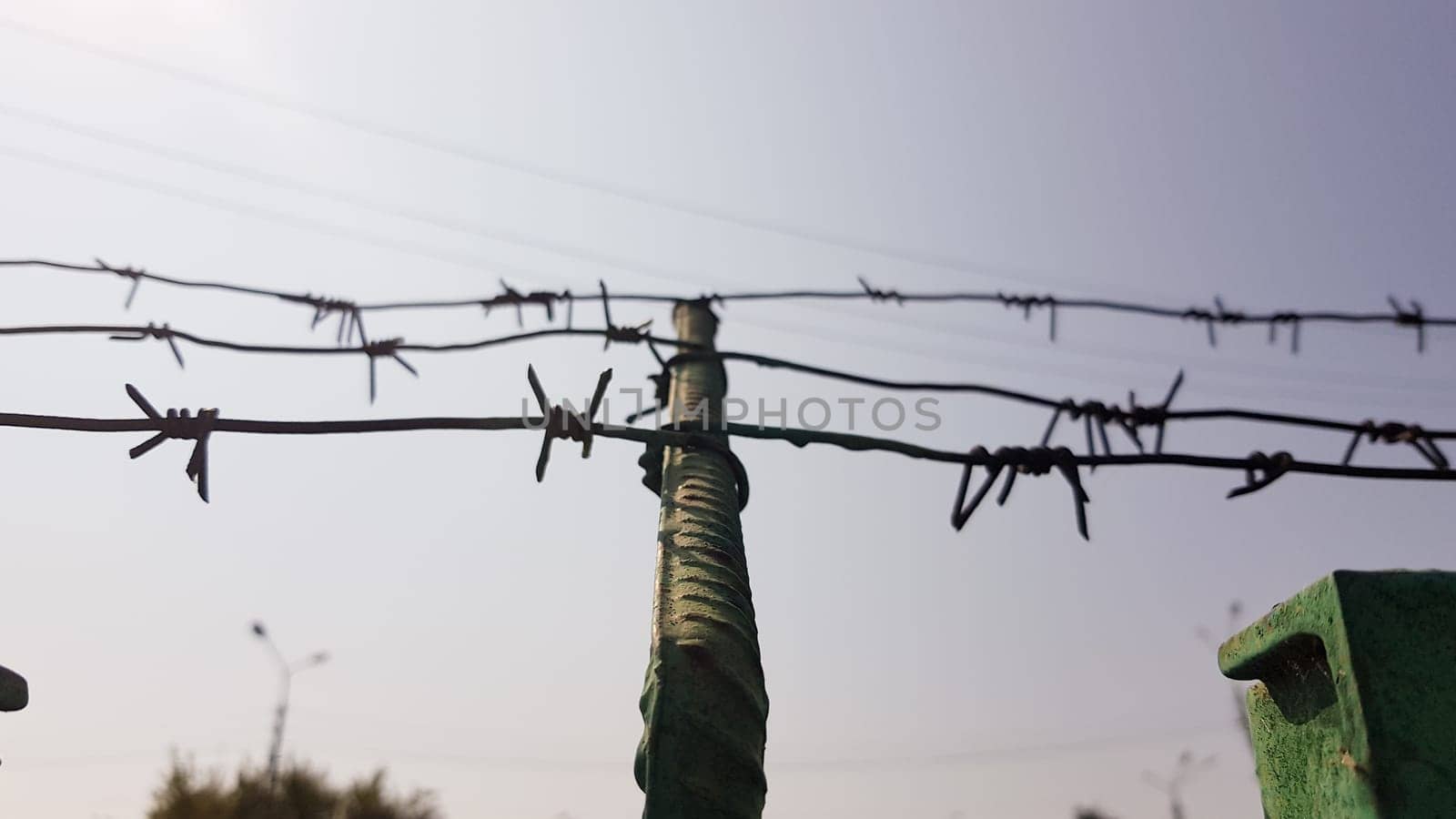 Barbed wire. Barbed wire on fence with blue sky to feel worrying. The silhouette of the old barbed wire fence and the sky at twilight