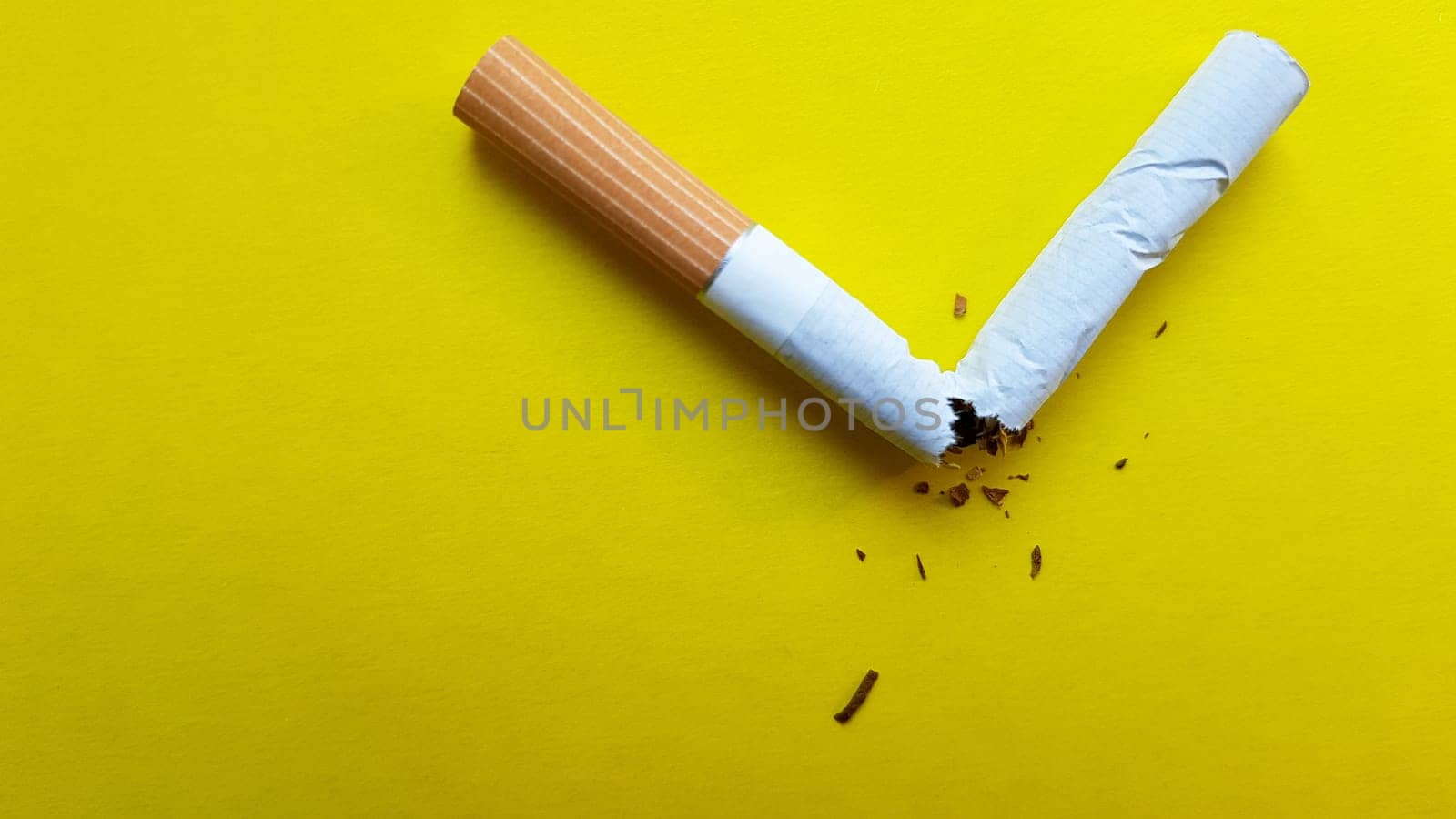Broken cigarette isolated on a yellow background. View from above.