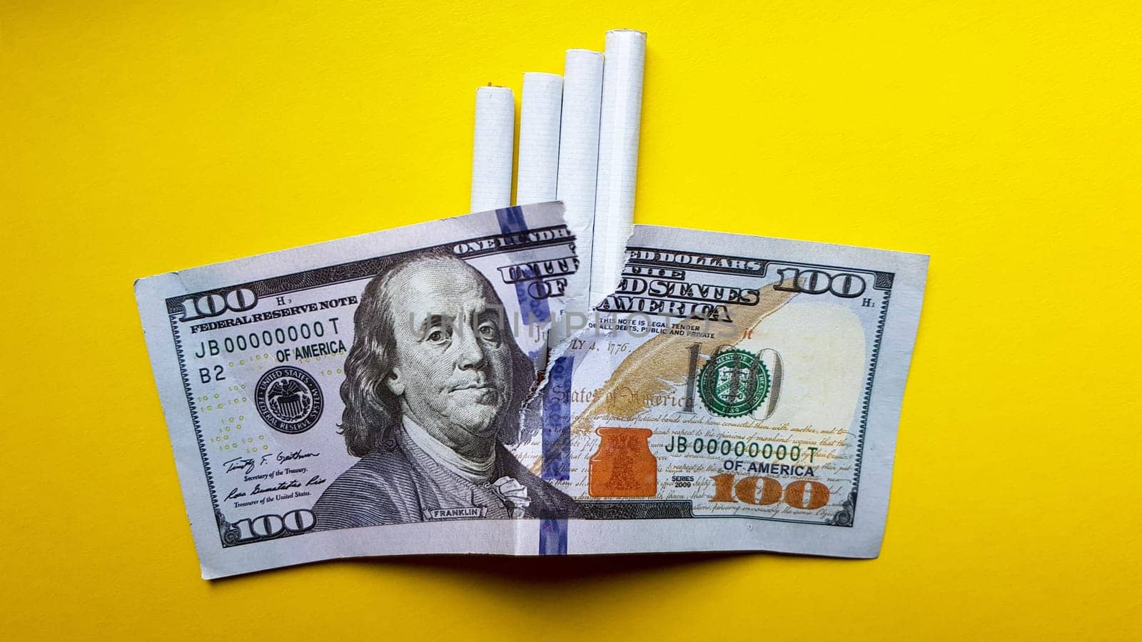 Classic cigarettes stand on one hundred US dollar bills. Cigarettes on a hundred dollar bill on a yellow background.
