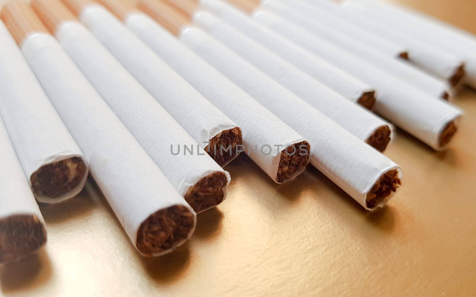 Image of several commercial cigarettes. pile of cigarettes on a gold background or concept of anti-smoking campaign, tobacco.
