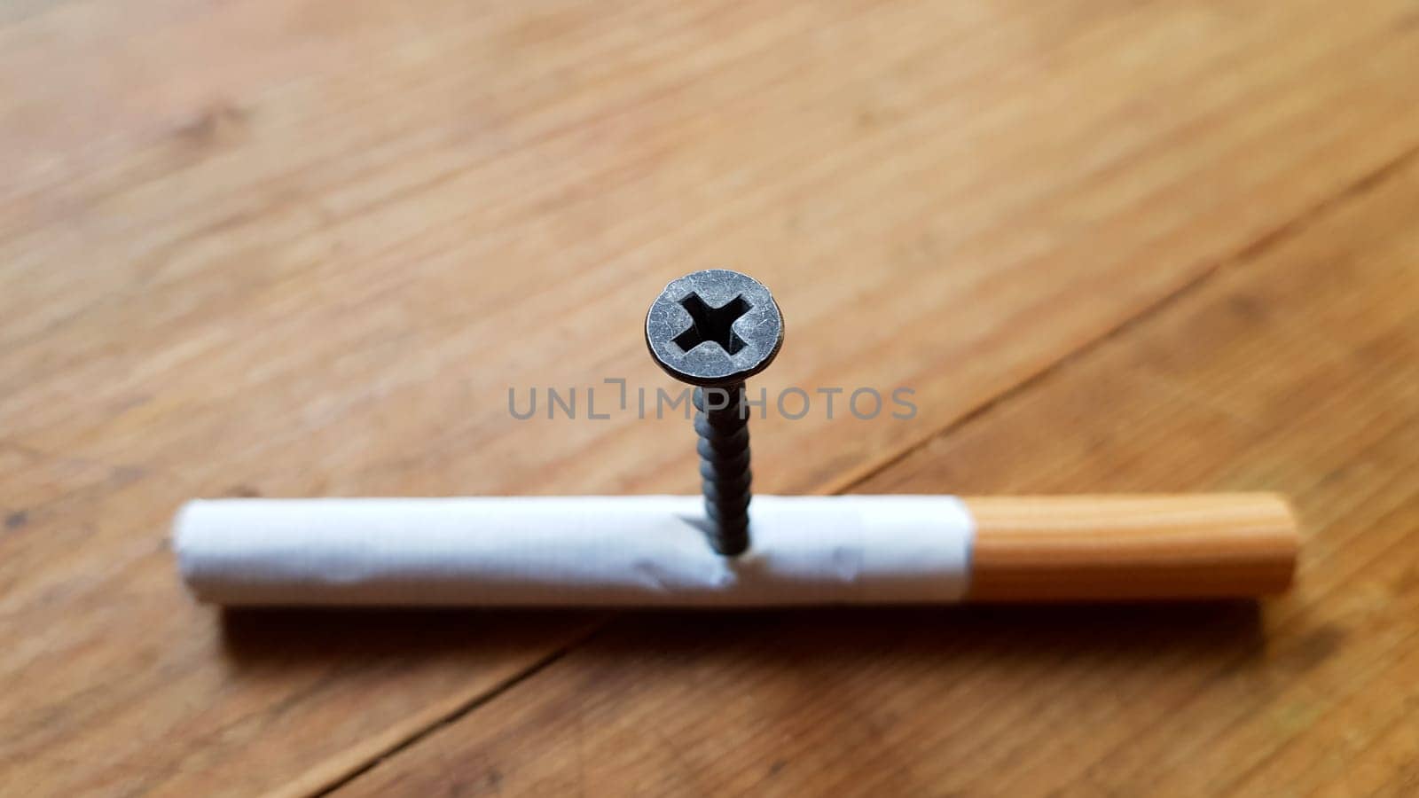Screw and yellow background. Screw screwed into a cigarette. Anti-smoking concept.