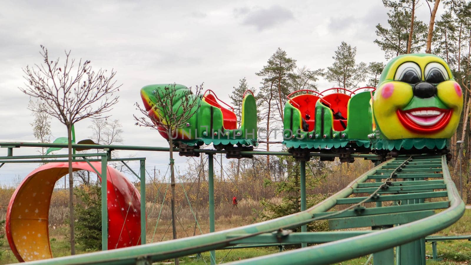 Ukraine, Kiev - October 24, 2019: roller coaster type attraction. Caterpillar-shaped roller coaster train in an amusement park. Carousels and leisure for children. Park in the fall without people.