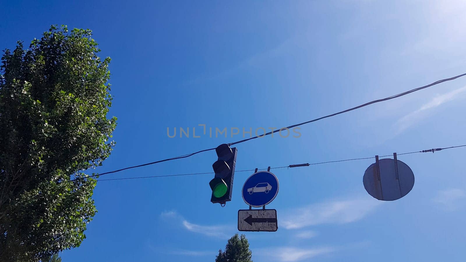 Traffic light and signs on the street close up with a burning green light.