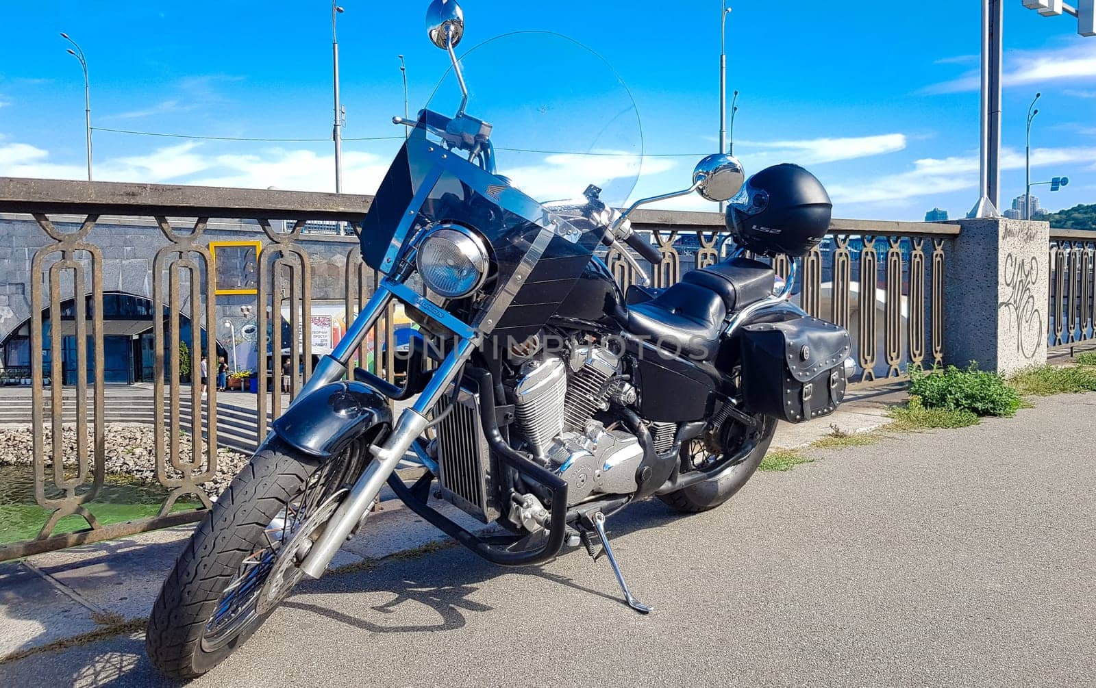 Ukraine, Kiev - September 08, 2019: Black vintage motorcycle parked on a bridge in the city center surrounded by city center buildings of urban environments. Hipster style, student dream, wild lifestyle.