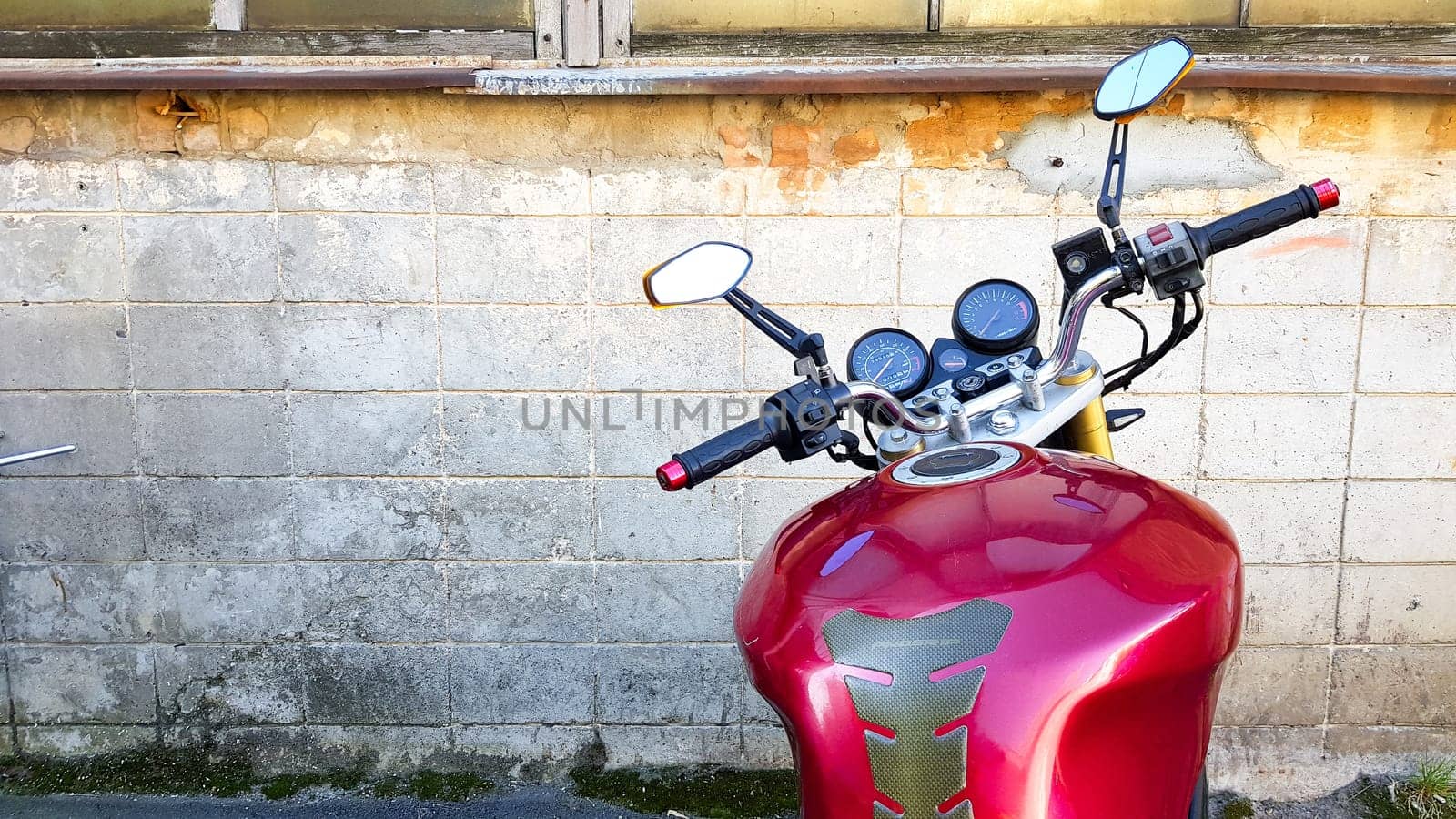 Ukraine, Kiev - September 8, 2019: Red motorcycle parked in a gray brick wall. First-person view, dashboard and steering wheel.