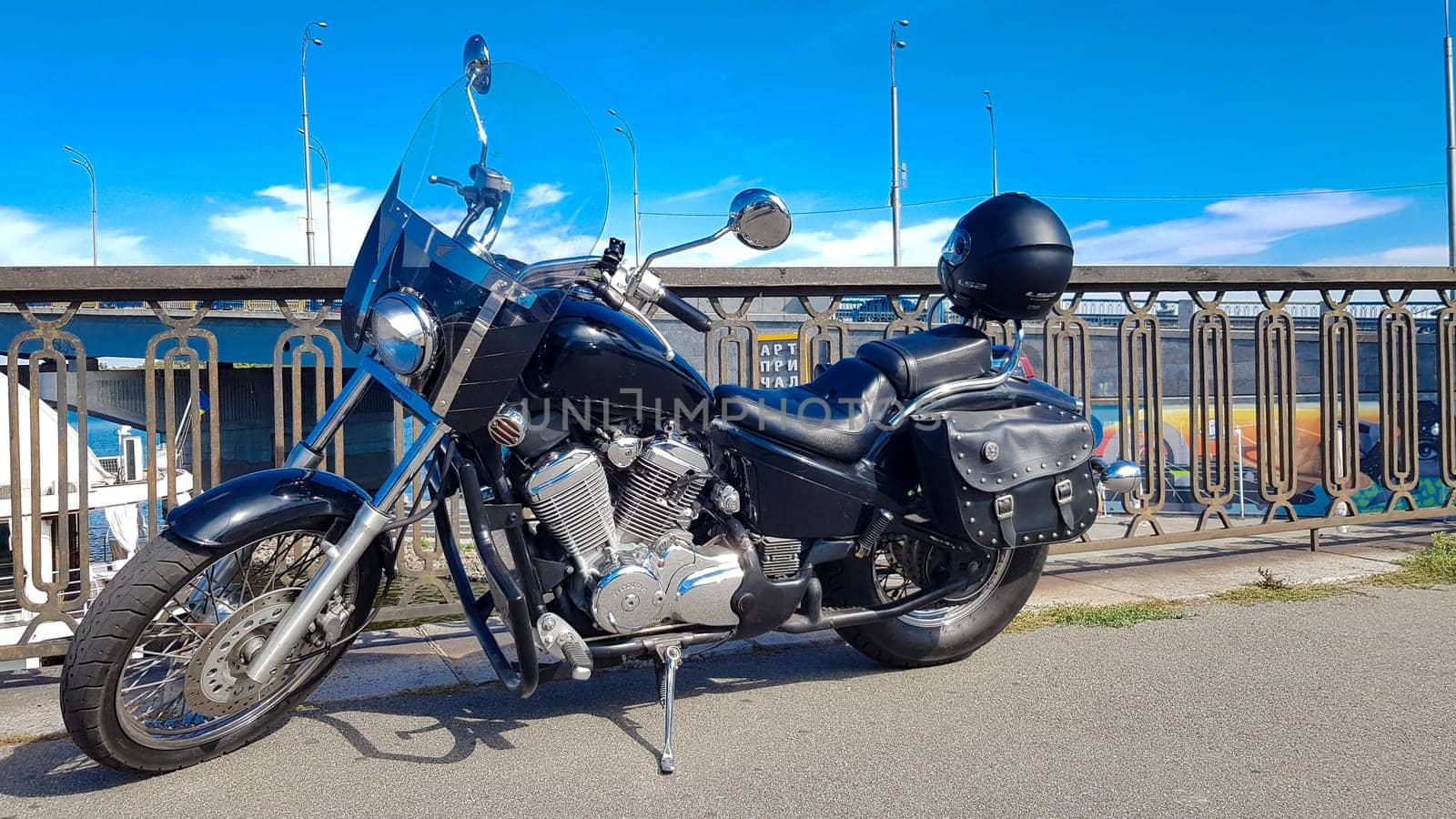 Ukraine, Kiev - September 08, 2019: Black vintage motorcycle parked on a bridge in the city center surrounded by city center buildings of urban environments. Hipster style, student dream, wild lifestyle.