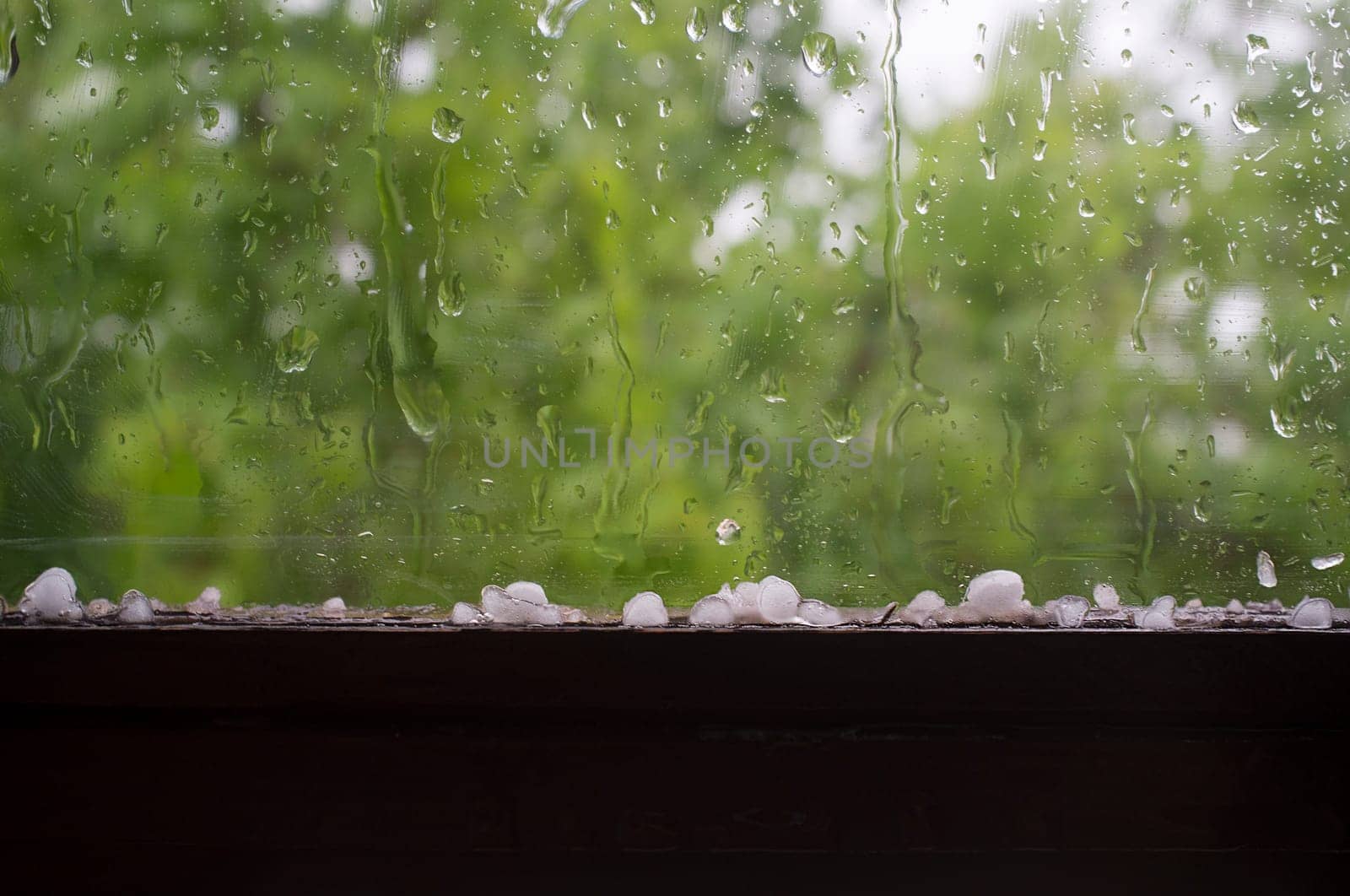 Hail over wooden window frame. Selective focus over green background